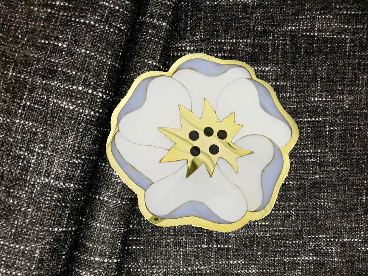 From Tiffany & Co.s designer Angela Cummings, an 18 Karat Allure flower, pansy brooch. The brooch is  inlaid with black jade, mother of pearl and blue lace agate.
Measuring 46.25mm in diameter
