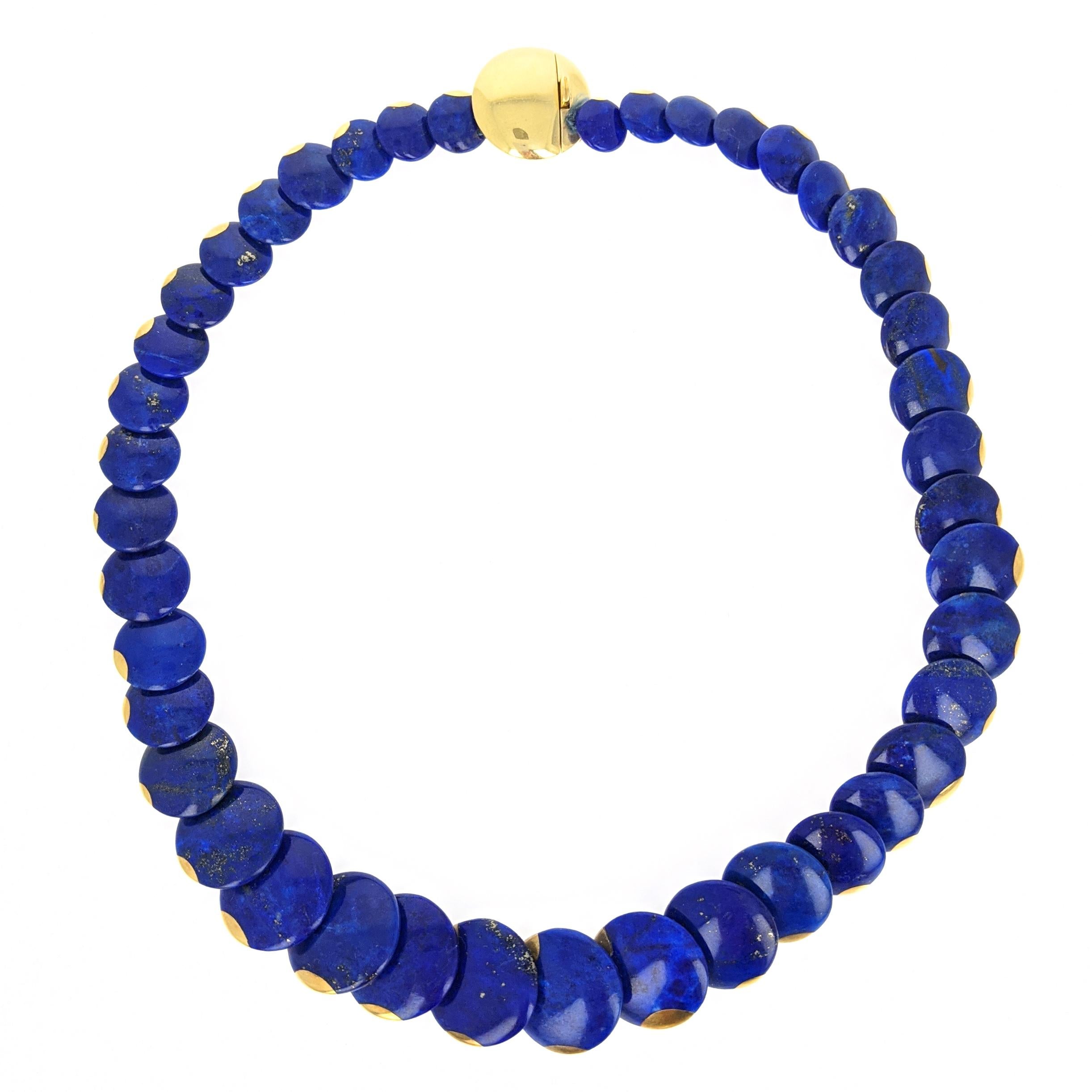 This sleek necklace by Angela Cummings for Tiffany and Company is composed of a single graduated strand of disk shaped lapis lazuli links. Each is accented by half round slivers of 18 karat yellow gold. It is secured by a disc shaped clasp signed