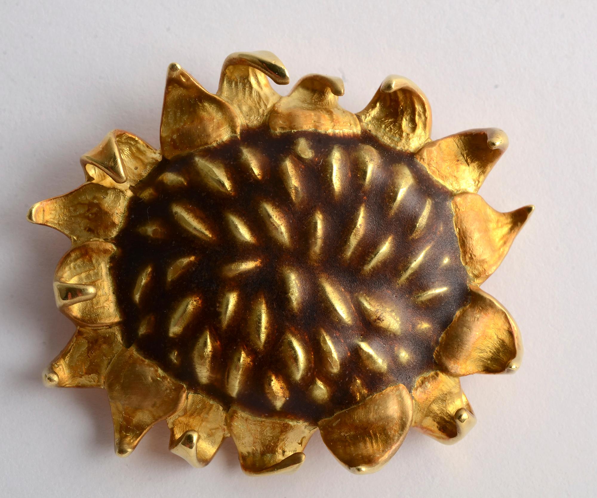 This 18 karat gold and enamel Sunflower brooch by Angela Cummings is wonderfully textured and dimensional. The height of the enamel floral center is intentionally irregular as are the triangular shaped petals. The brooch measures 1 5/8 inches in