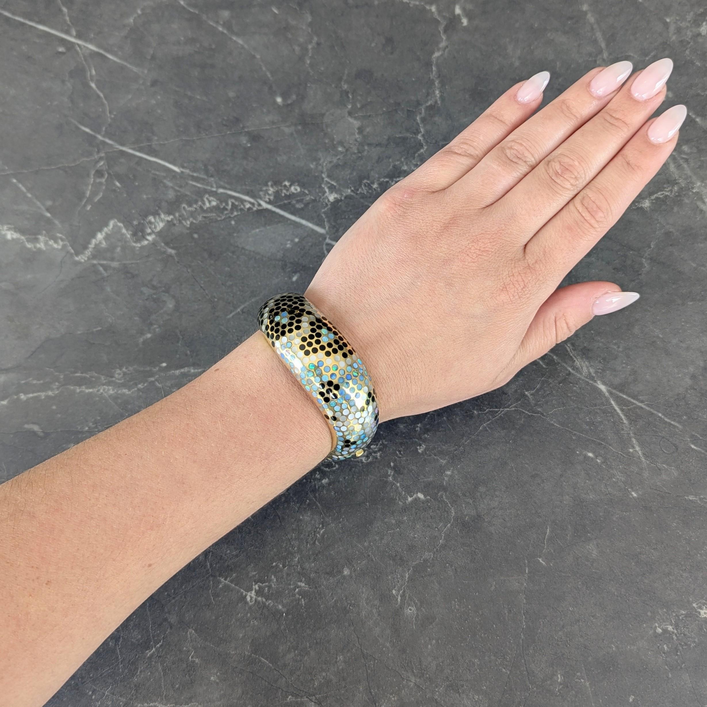 Designed as a wide bangle bracelet with undulating edges inlaid with snakeskin polka dot pattern
Featuring opal, mother-of-pearl, and onyx circles alternating in pattern and measuring 2.7 mm
Opaque black with spectral play-of-color, iridescent