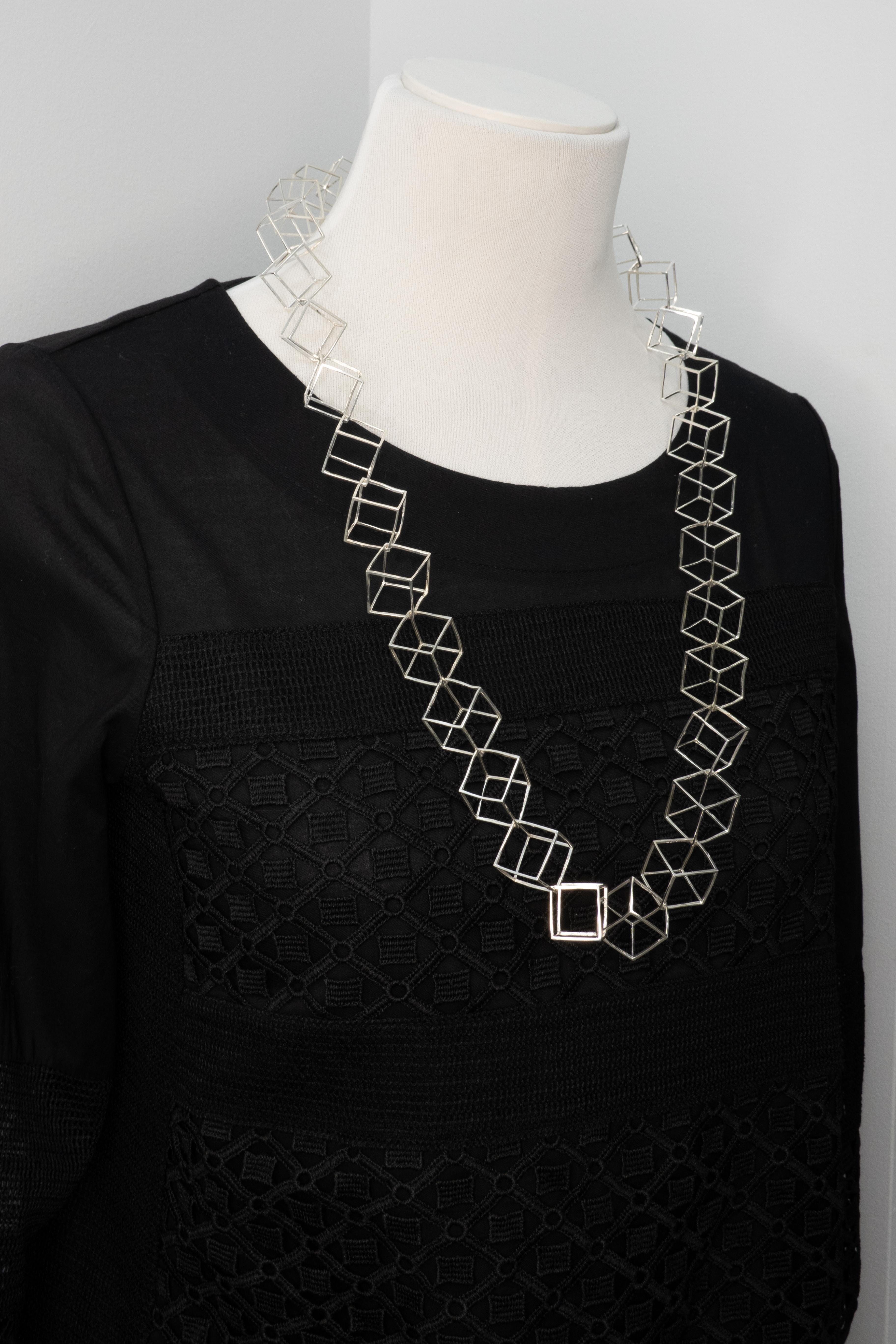 Una rara e da collezione collana scultorea in argento sterling disegnata nel 1984 da Cummings. Il pezzo d'avanguardia presenta una serie interconnessa di cubi tridimensionali traforati, ognuno dei quali è contrassegnato individualmente dalla scritta