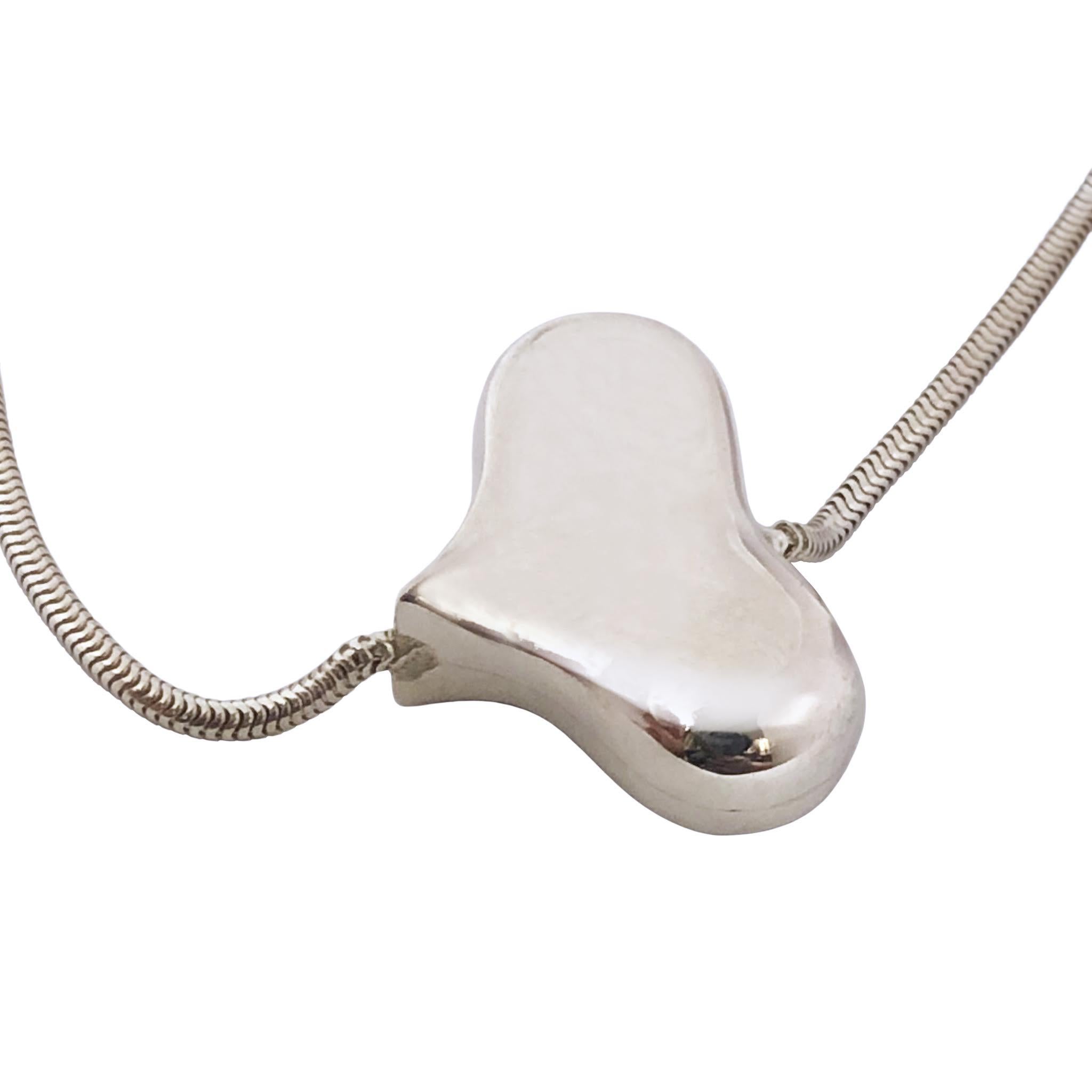 Circa 1980s Angela Cummings Sterling Silver Puffed Heart Necklace, a stylized Heart that is stationary and measuring 1 X 5/8 inch and 1/4 inch thick. Suspended from a 2 M.M. Snake chain, 30 inches in length.