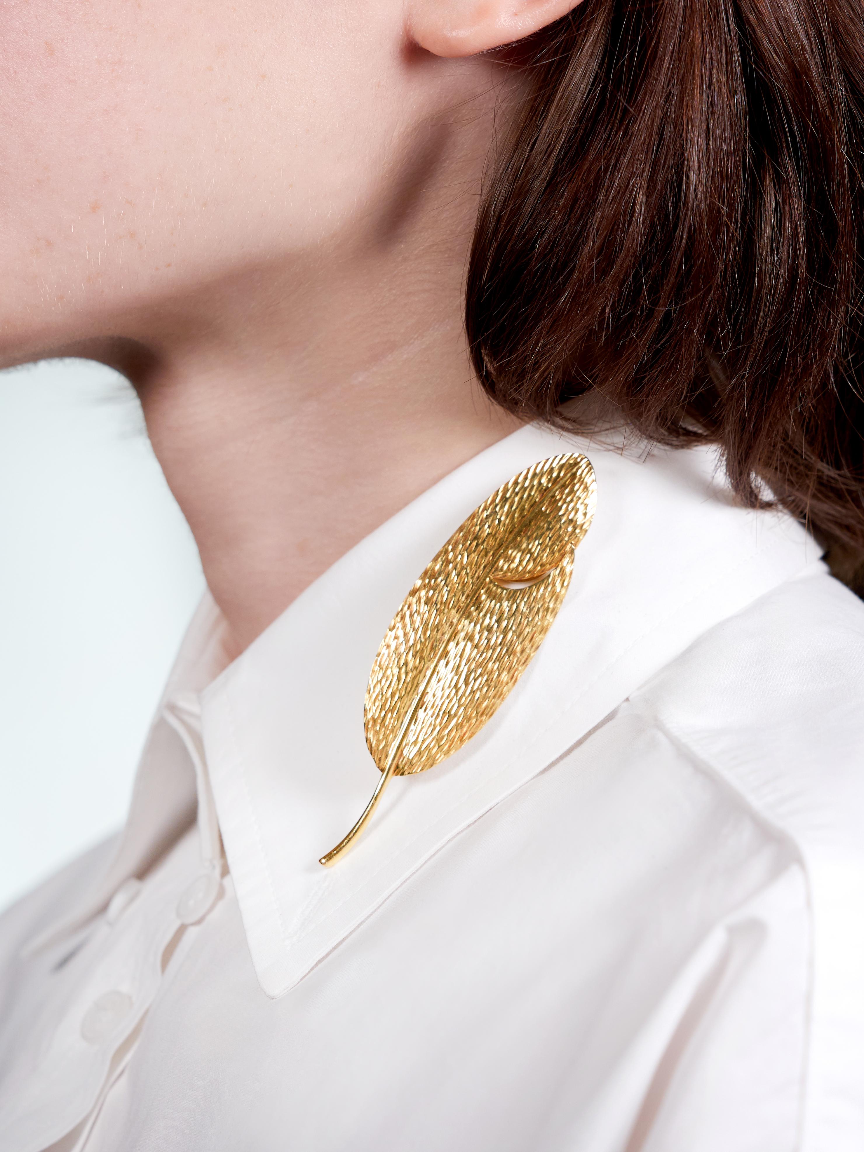 Designed s a stylized oval shaped leaf with stem
Featuring a pierced swoop and linear texture
With high polish finish
Completed by hinged pinstem with locking closure
Stamped for 18 karat gold
Fully signed for Angela Cummings for Tiffany &