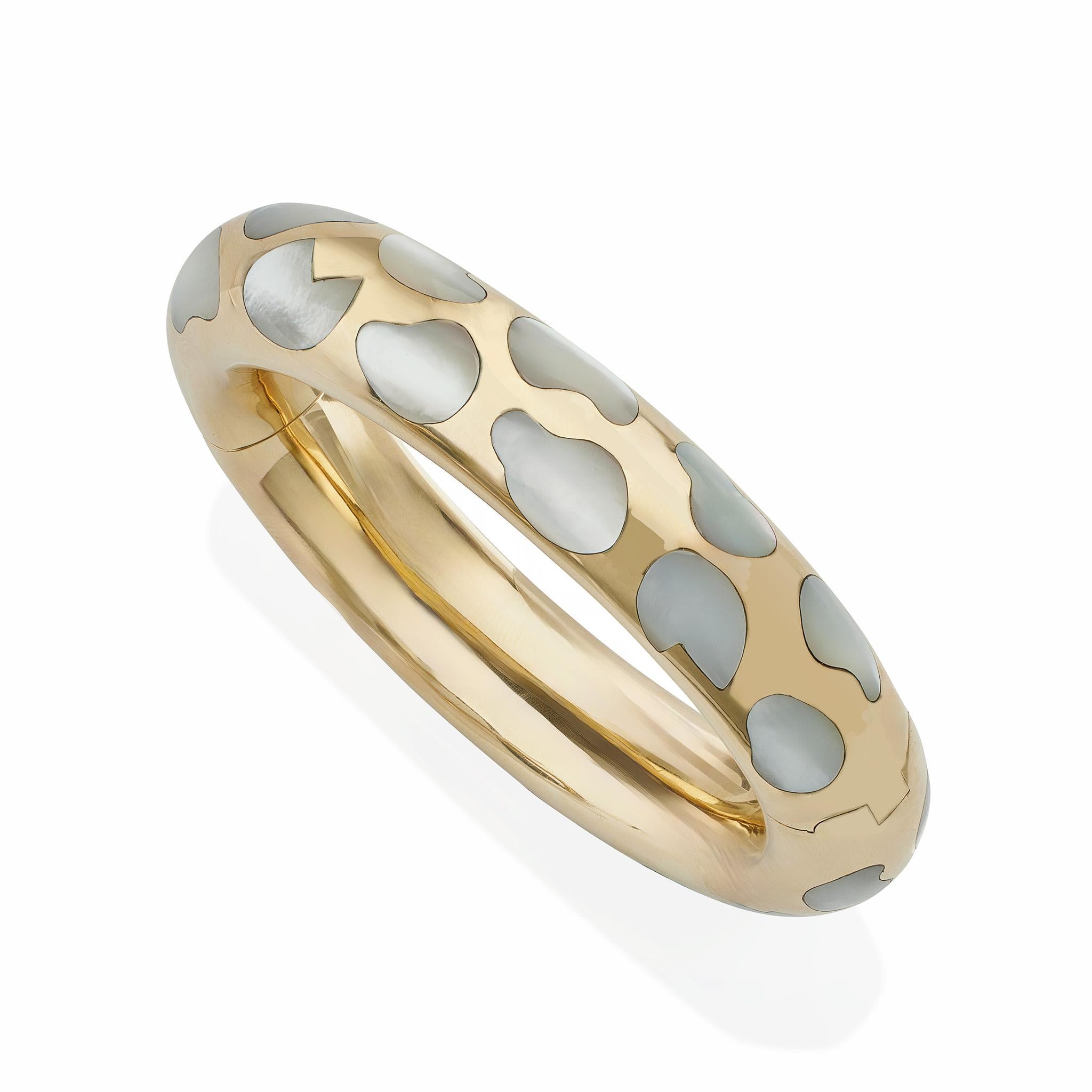Created by Tiffany & Co. in the 1970s-1980s, this 18K gold and mother-of-pearl bracelet was designed by Angela Cummings. The hinged, polished 18K gold bangle is inlaid with irregular spots of mother-of-pearl resembling a leopard skin that are flush