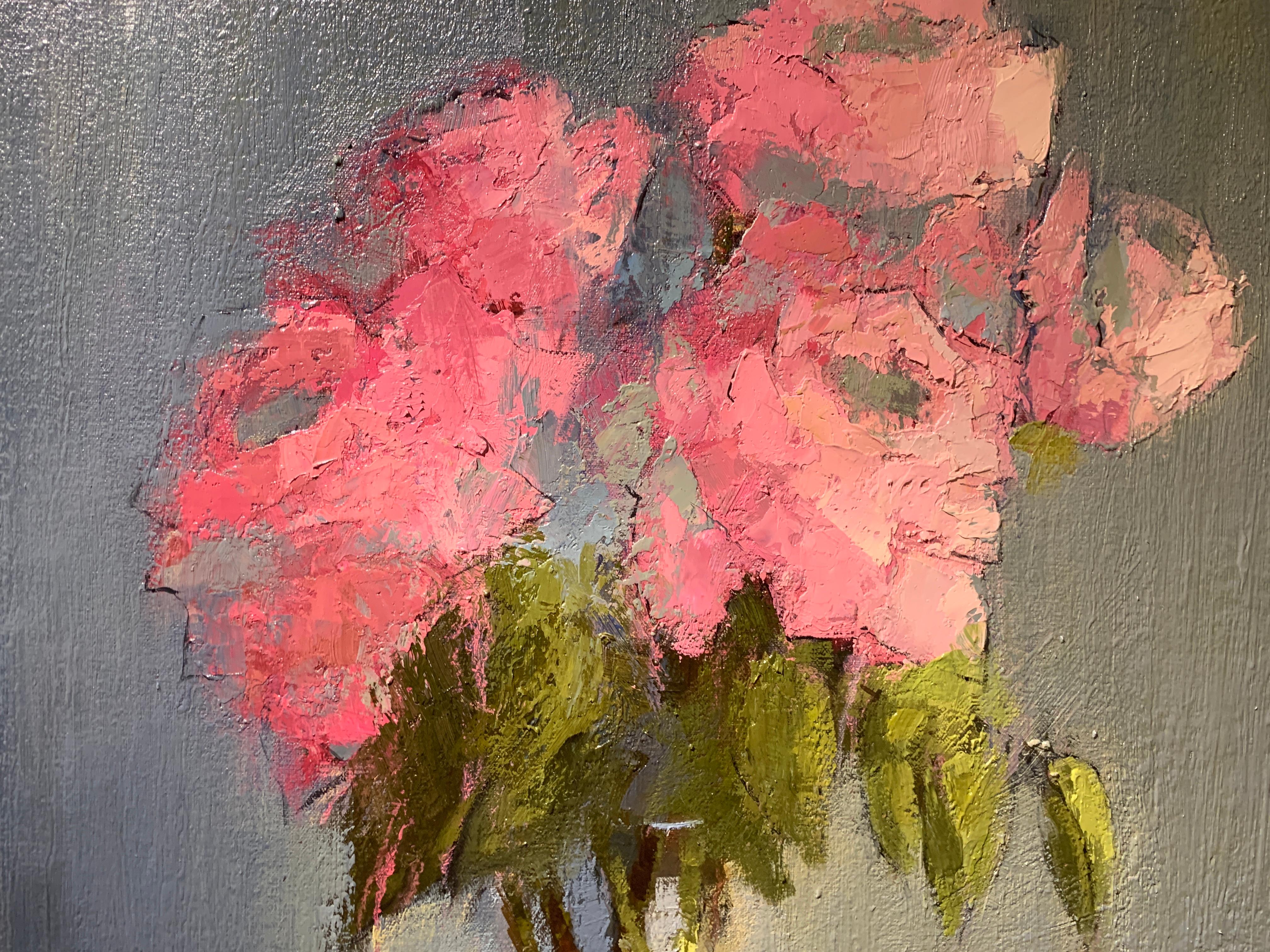 'Party Pinks' is a medium sized Impressionist floral oil on canvas painting created by American artist Angela Nesbit in 2019. This exquisite still-life features a delicate bouquet of coral flowers, displayed in a simple glass vase on a blurred