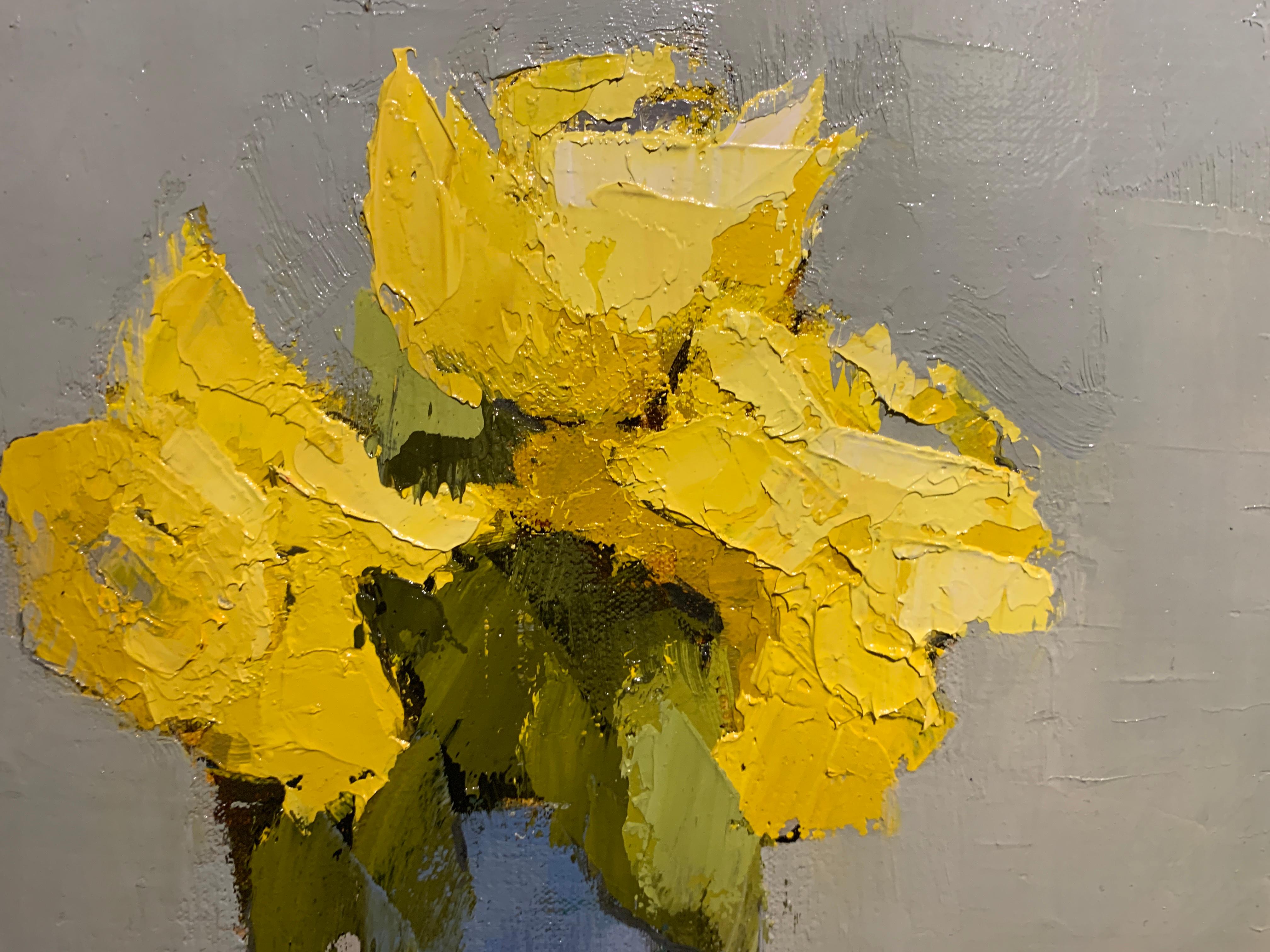 This petite impressionist 2019 painting from American artist Angela Nesbit depicts yellow flowers in a glass vase.  Green, blue, grey and yellow can be found in the soft and subtle palette.  The artist signed this piece on the bottom right.