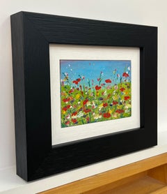 Miniature Red Poppy Flowers in a Wild Green Meadow with a Blue Sky in England
