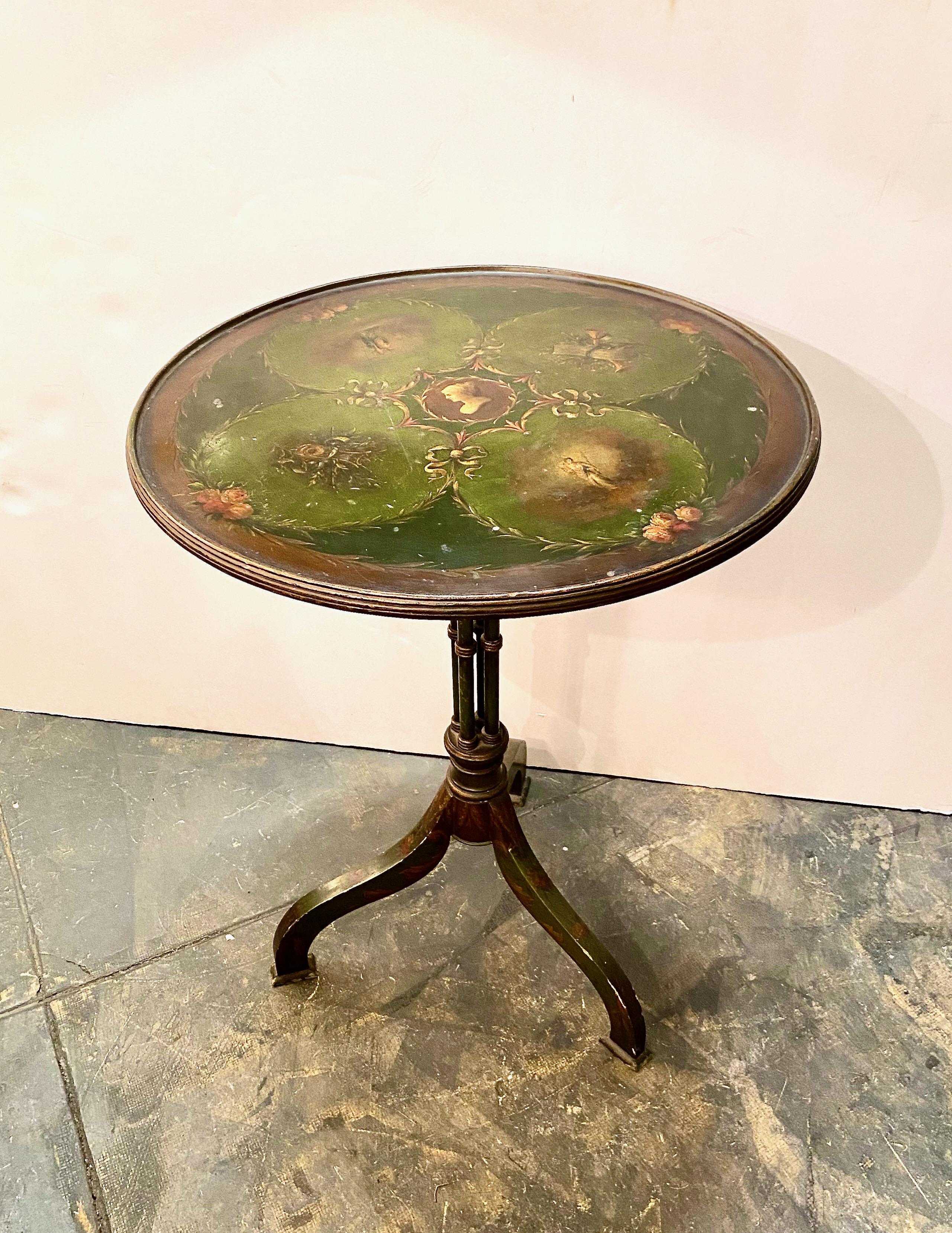 This is a charming early 19th century small tilt-top table. The top is painted in the style of Angelica Kauffman; the four-column pedestal bases is detailed in florals over a deep Italian green. The painted surface is in overall good to very good