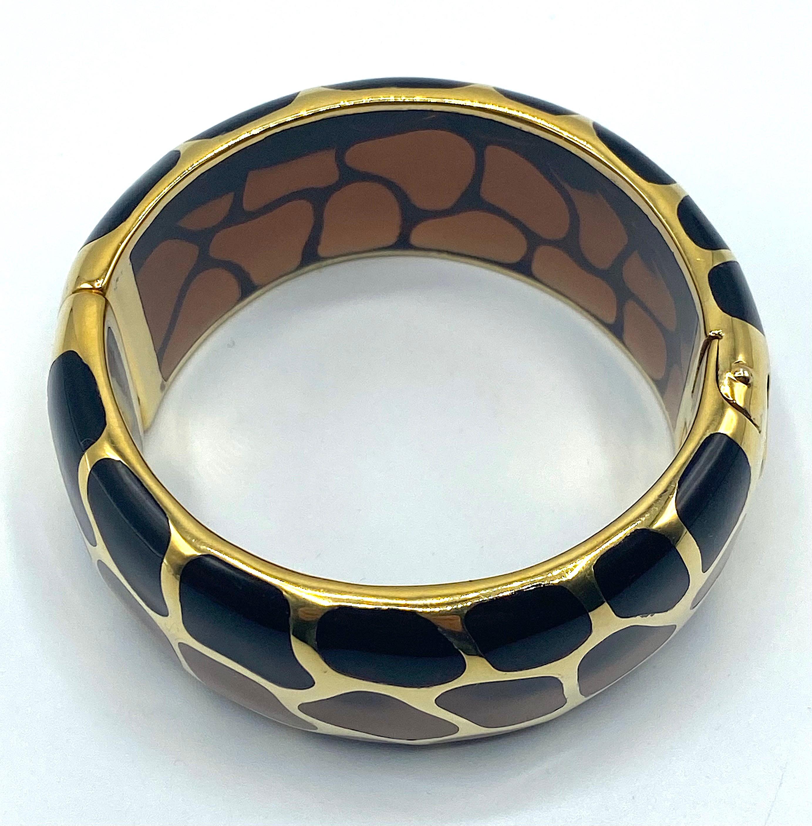 A beautiful animal motif bangle from the Safari collection by French jewelry company Angélique de Paris. The bangle lightly oval in shape. It is a transparent brown resin overlaid with .925 sterling silver and 18K gold plate. It is a clamper style