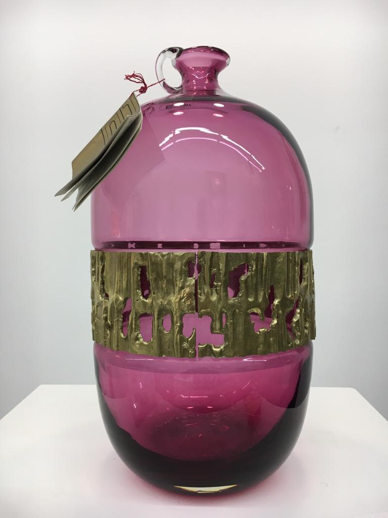 “Iside” is a beautiful, rare vase designed by Angelo Brotto, manufactured by Esperia in Italy around 1980.

This original vintage piece is made of beautiful purple / fuchsia coloured glass in an elegant shape and with brass details. The brass ring