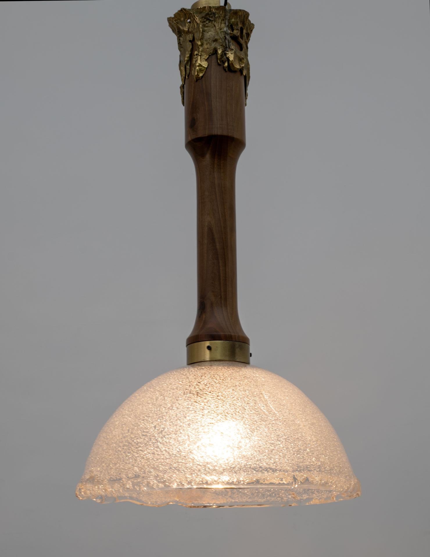 This particular ceiling lamp is equipped with a Graniglia Murano glass lampshade and a solid wood rod. The upper end is surrounded by an irregular bronze casting engraved with the author's name 