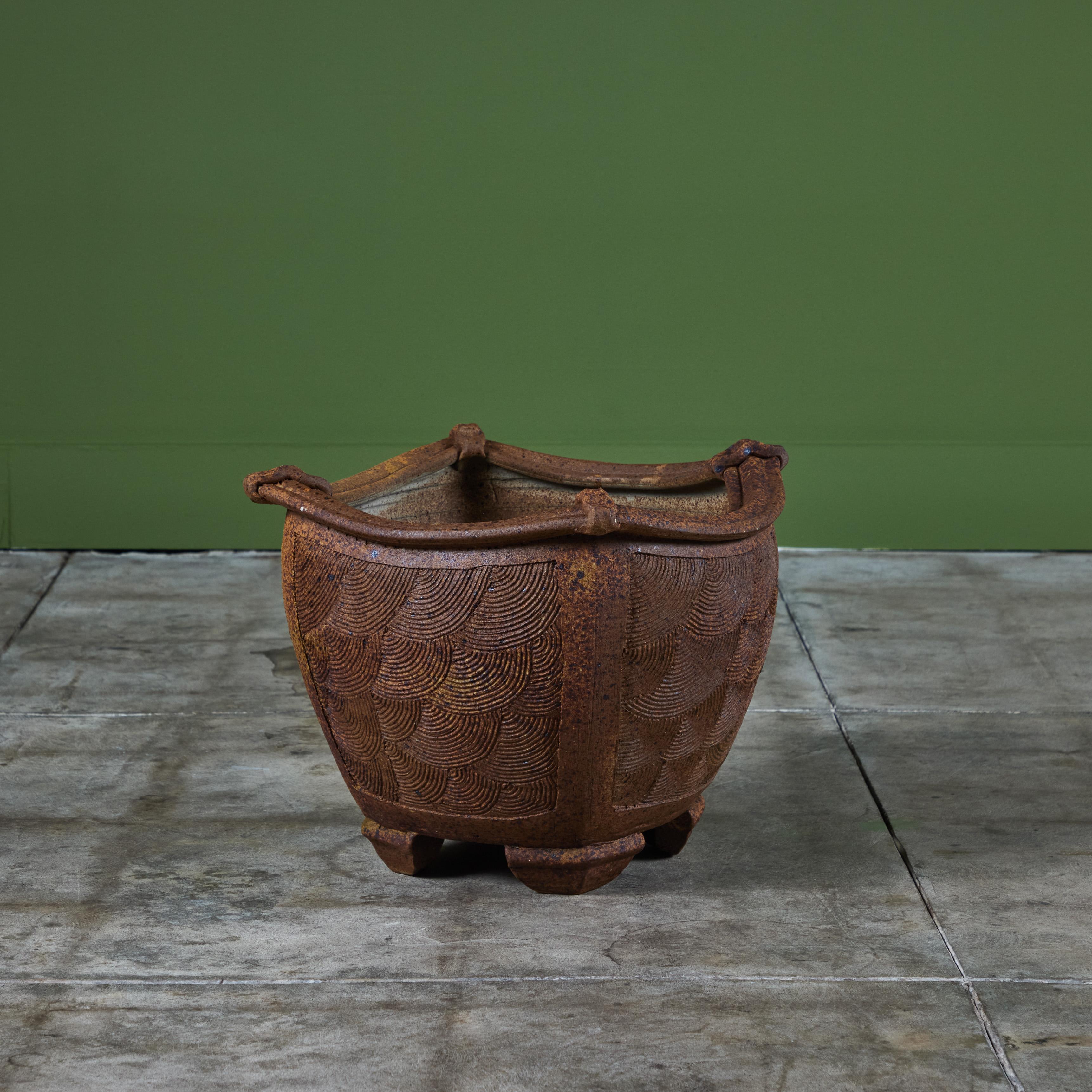 Hand thrown stoneware planter by Italian American artist Angelo Garzio, c.1970, USA. This planter features a square vessel with rounded sides showcasing a circular incised pattern. The rim of the planter has a slightly curved ornate lip. The planter
