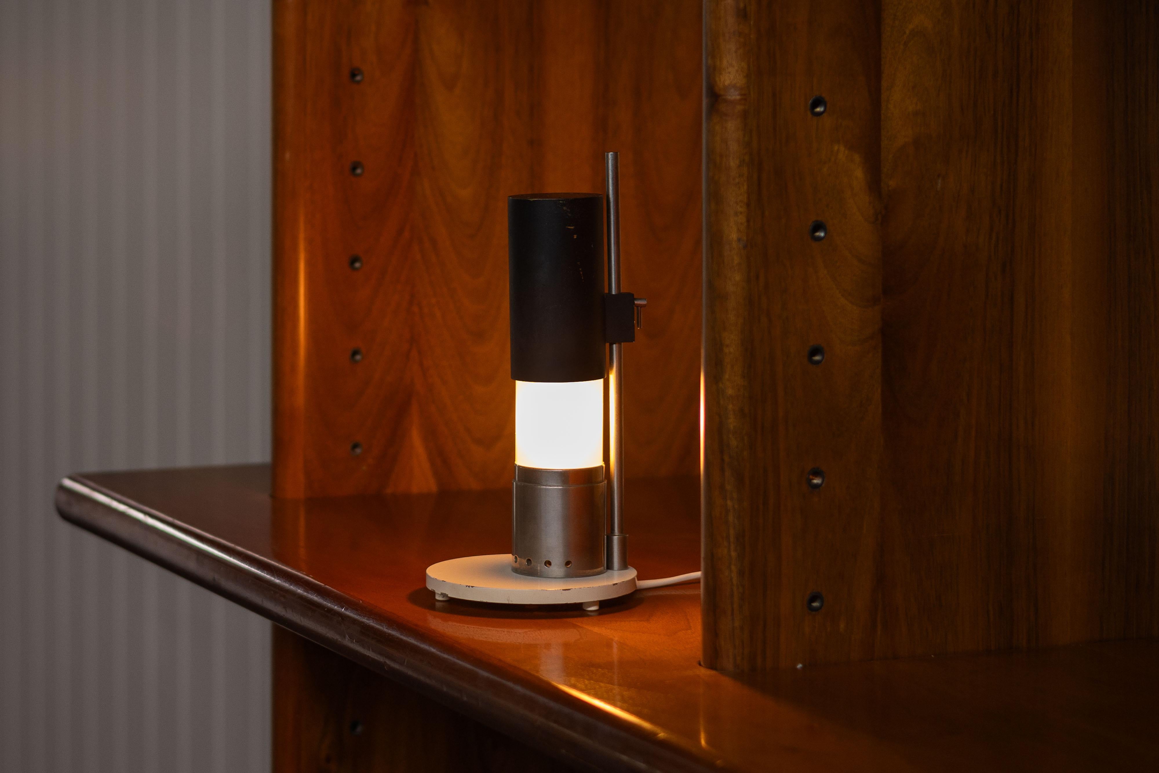The model 12445 table lamp, designed by Angelo Lelii and manufactured by Arredoluce in Italy in 1954, is a refined example of mid-century architectural design. This compact yet striking lamp reflects Lelii’s mastery in form and function. Its design