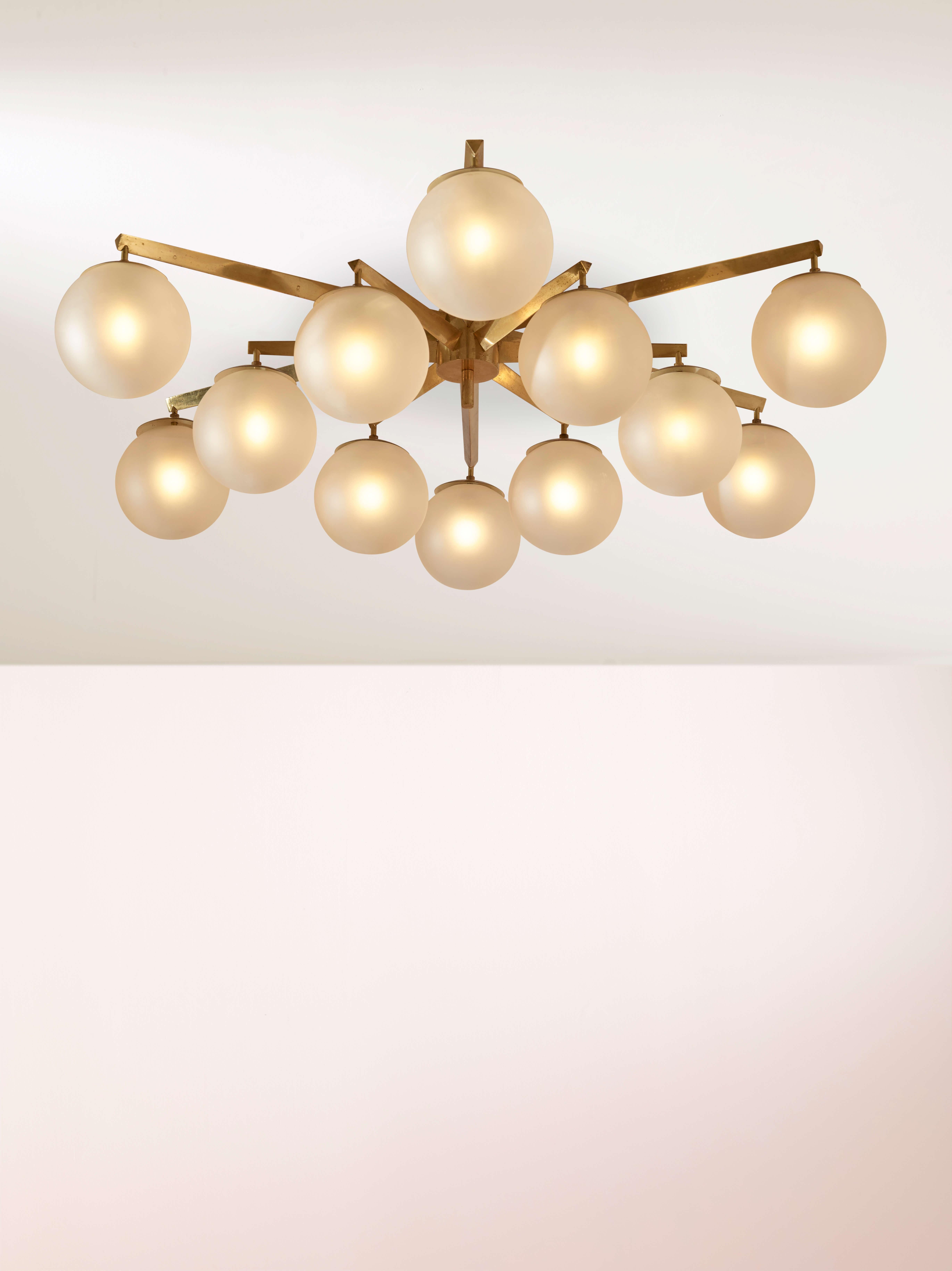 An exceptional and authentic ‘Stella a 12’ chandelier or ceiling light designed by Angelo Lelii for Arredoluce, Italy, circa 1958. This refined piece features twelve spherical glass shades with an acid-etched finish, elegantly suspended from a brass