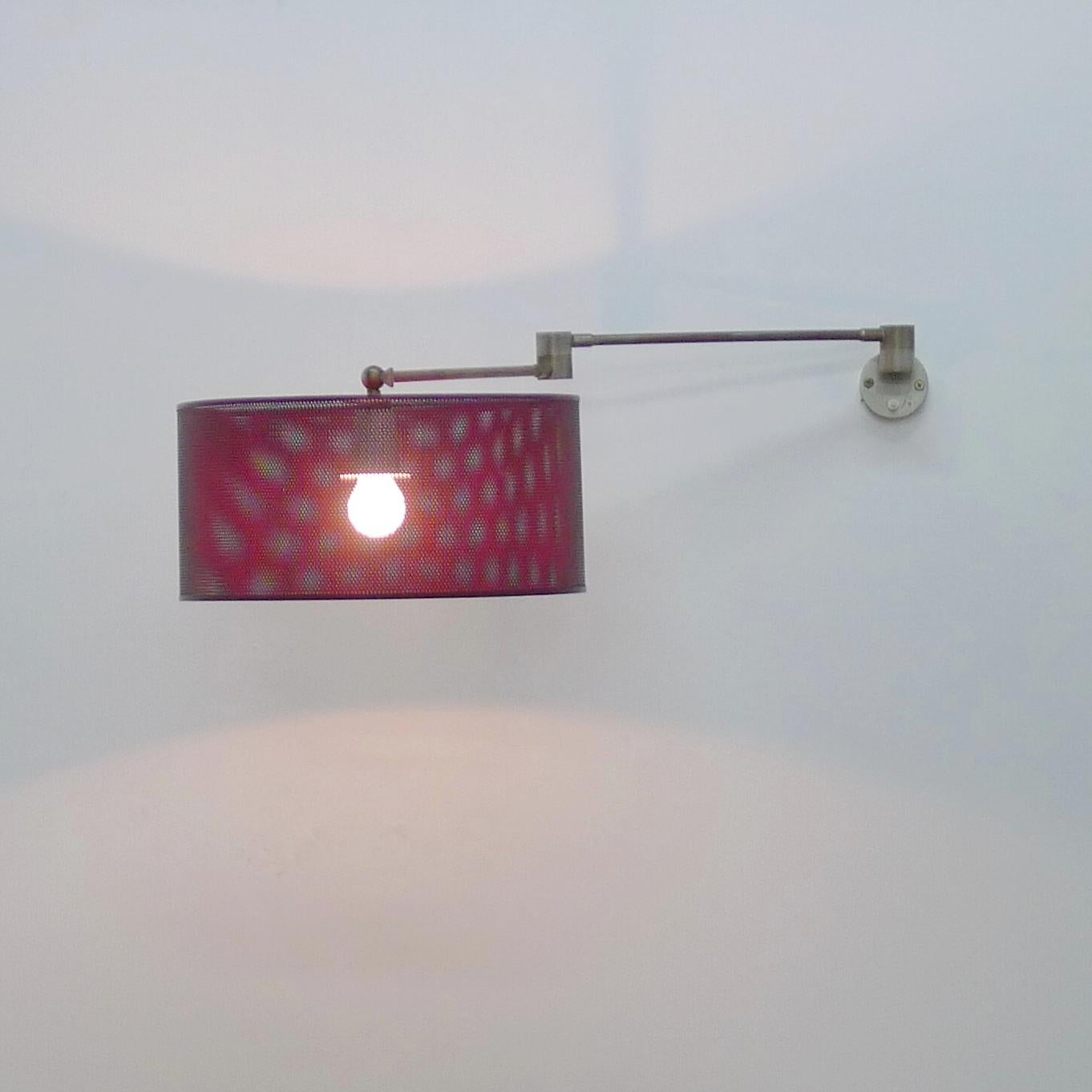 Angelo Lelii für Arredoluce, verstellbare Wandleuchte mit rot lackiertem Stahlgeflechtschirm auf einem voll beweglichen Messingrohrträger mit zentralem Scharnier, das es ermöglicht, den Schirm in viele Richtungen zu bewegen, um das Licht dort