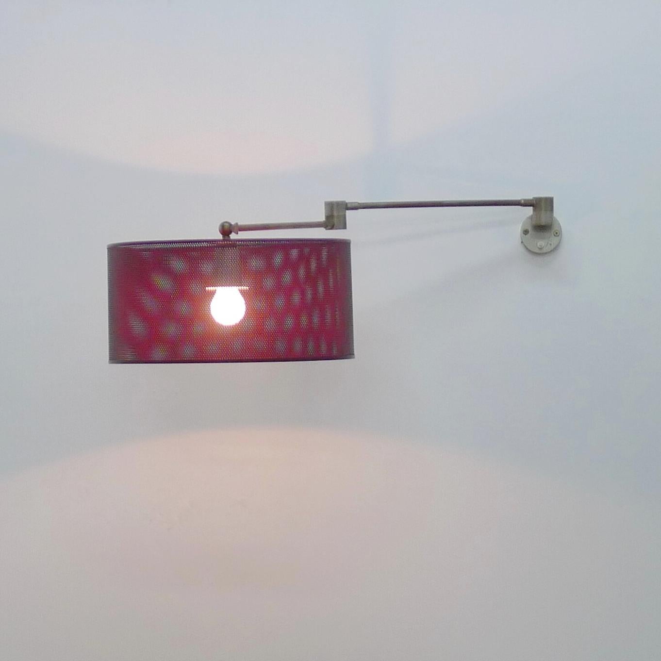 Angelo Lelii for Arredoluce, Adjustable Wall Light with red lacquered steel mesh shade on a fully articulated tubular brass support with central hinge which allows the shade to be moved in many directions to shed light where required.  The circular