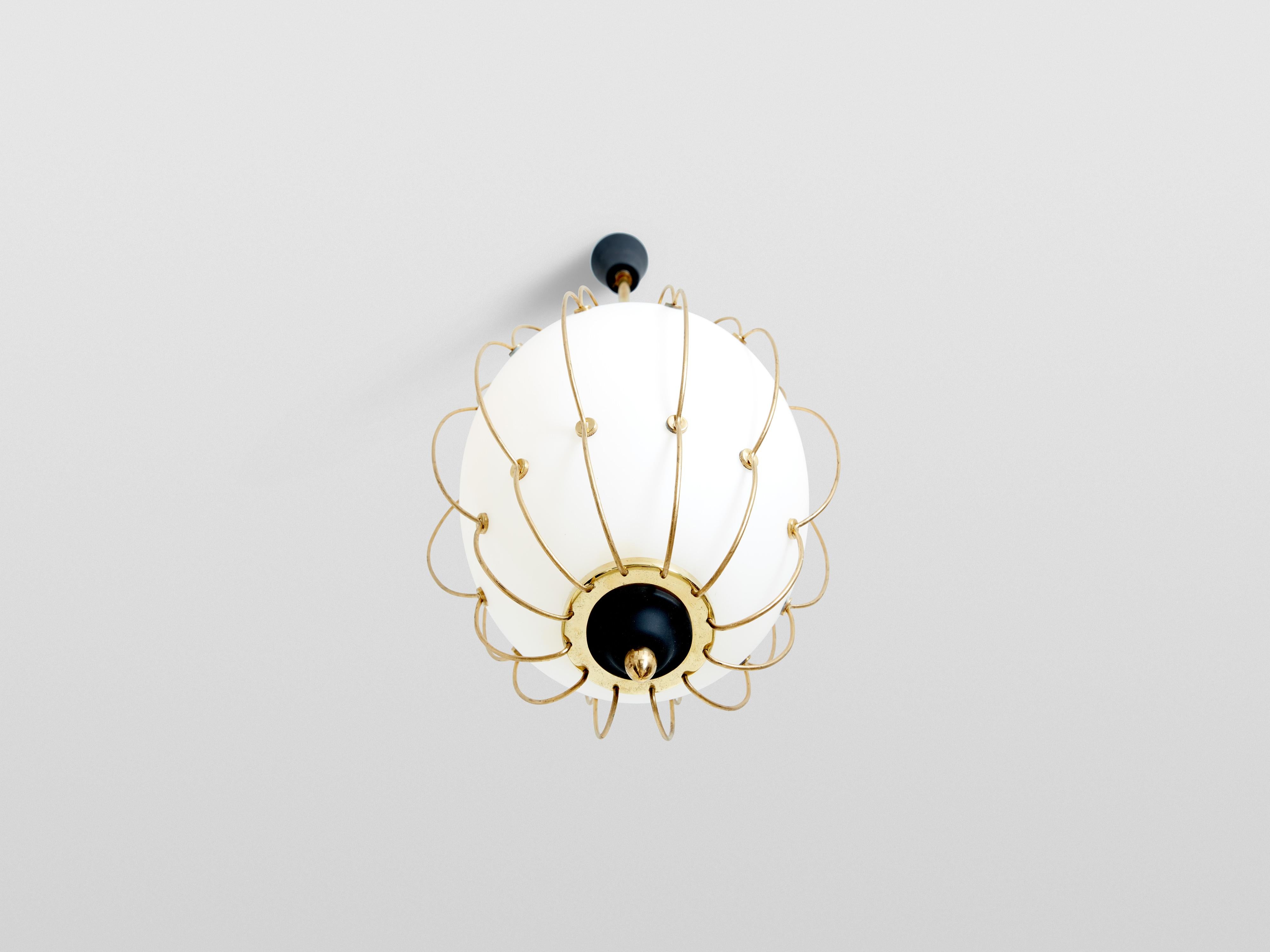 This white opaline glass, brass, and metal chandelier was designed by Angelo Lelii for Arredoluce in 1958. Featuring a meticulously crafted abstract structure made from curved brass rods surrounding the opaline glass shade, this luminaire is a