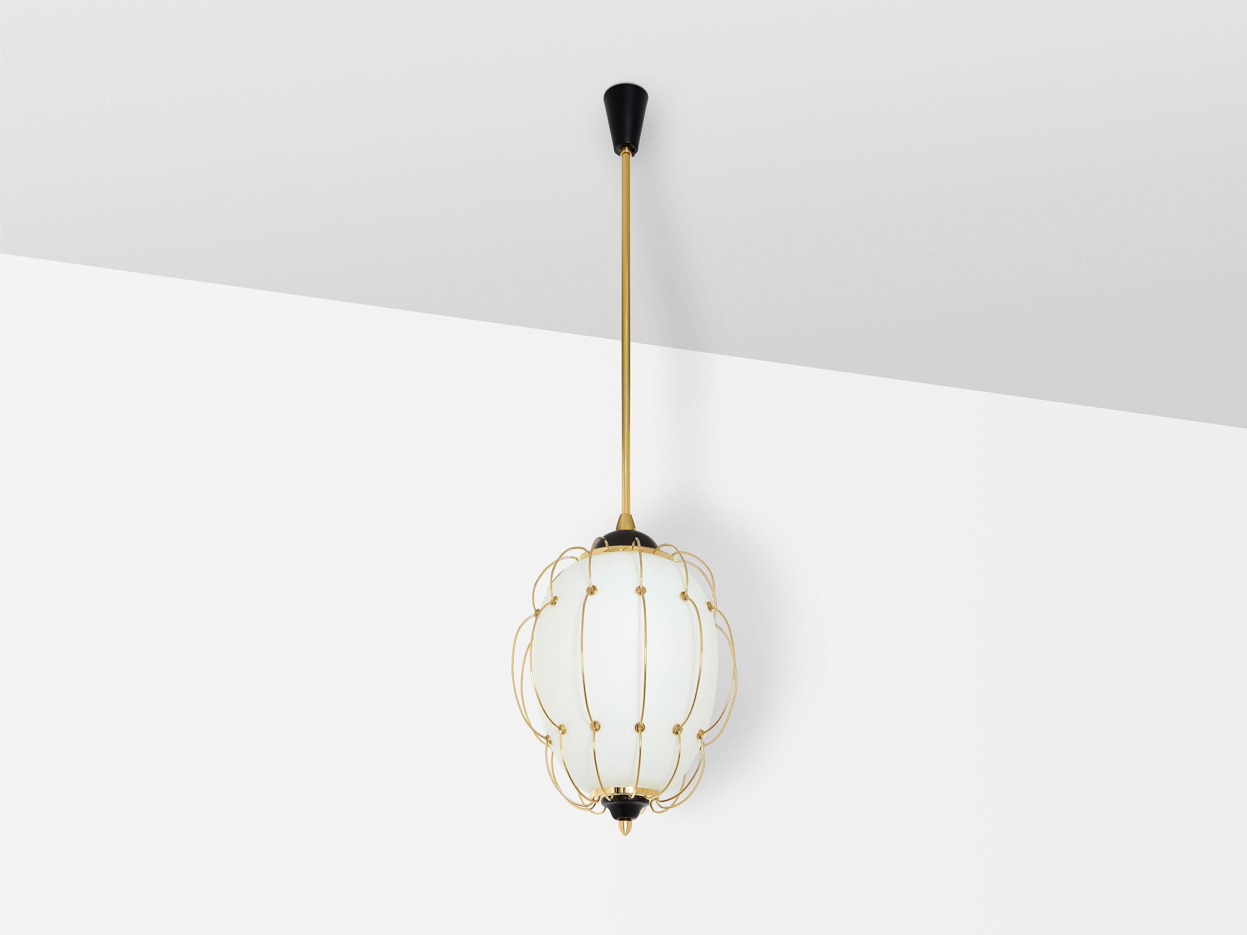 This white opaline glass, brass, and metal chandelier was designed by Angelo Lelii for Arredoluce in 1958. Featuring a meticulously crafted abstract structure made from curved brass rods surrounding the opaline glass shade, this luminaire is a