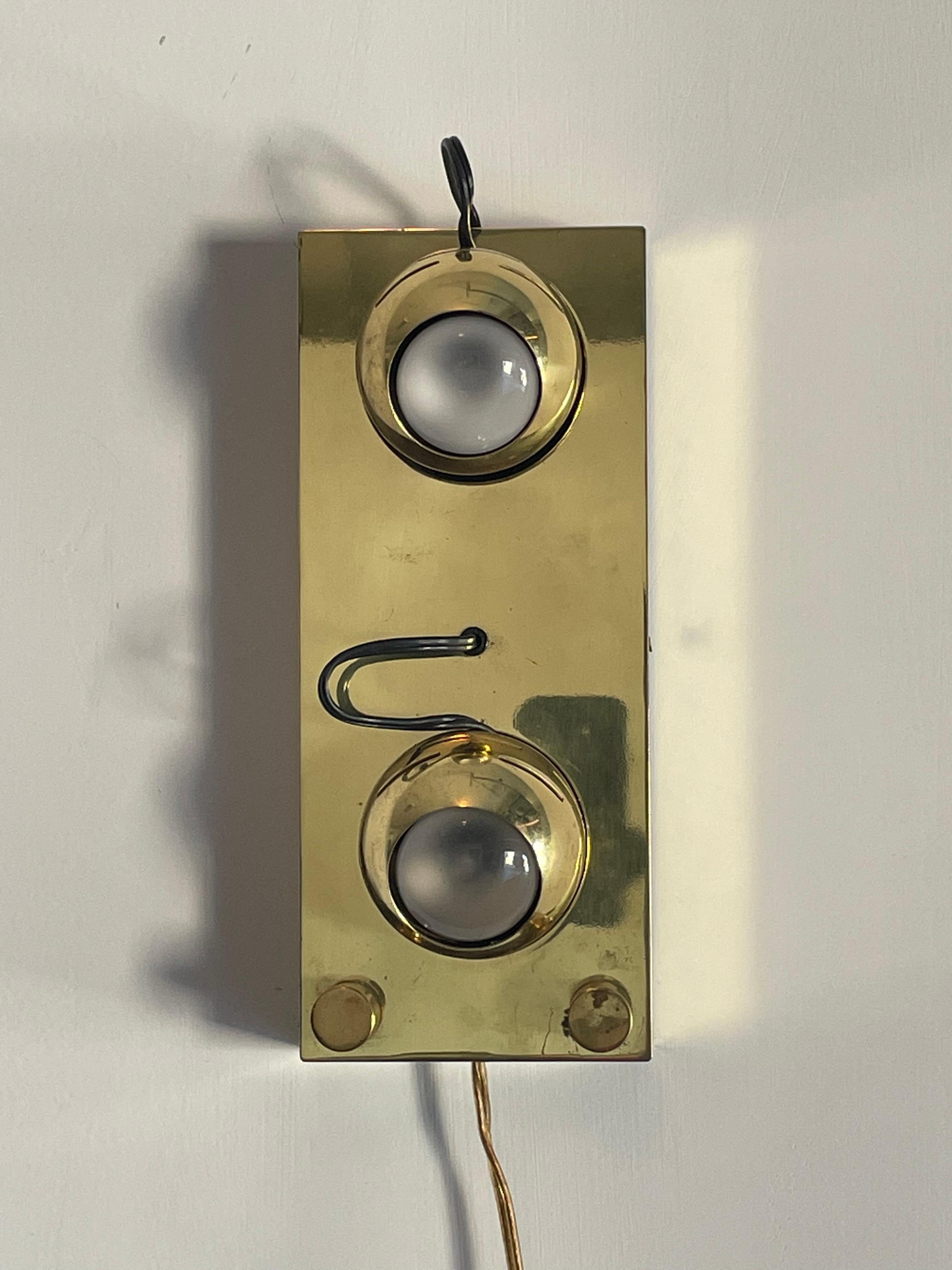 A rare wall light or sconce designed by Angelo Lelii for Arredoluce. Light is polished brass and features two “eyes” that are magnetic and can be removed angled in nearly any direction via a magnet. Light uses dimmable knobs to adjust each bulb