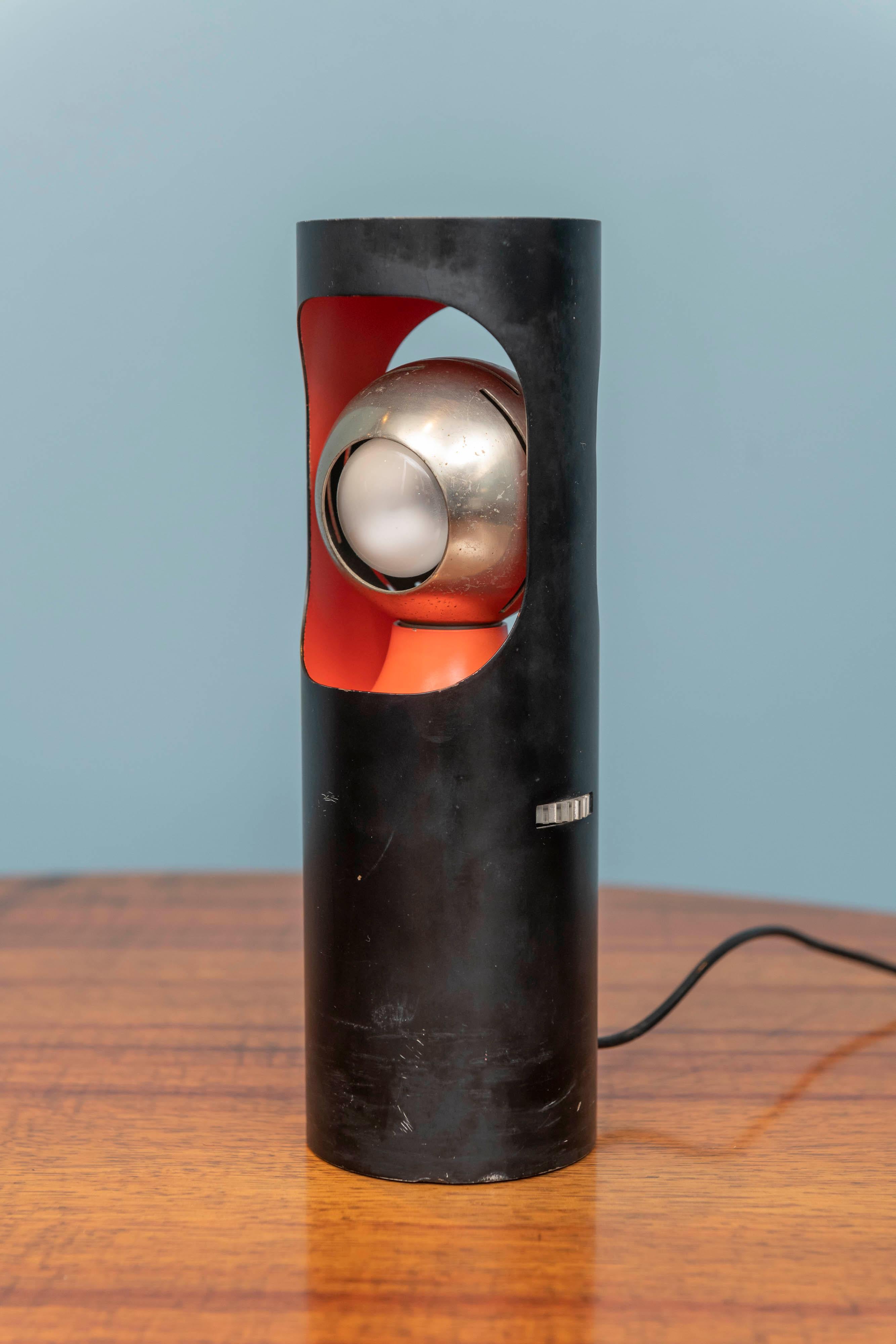 Angelo Lelli design eye spot table lamp for Arredoluce, Italy. Heavy black lacquered steel cylinder form body with a vibrant orange painted interior and an adjustable chrome spotlight, stamped on base.