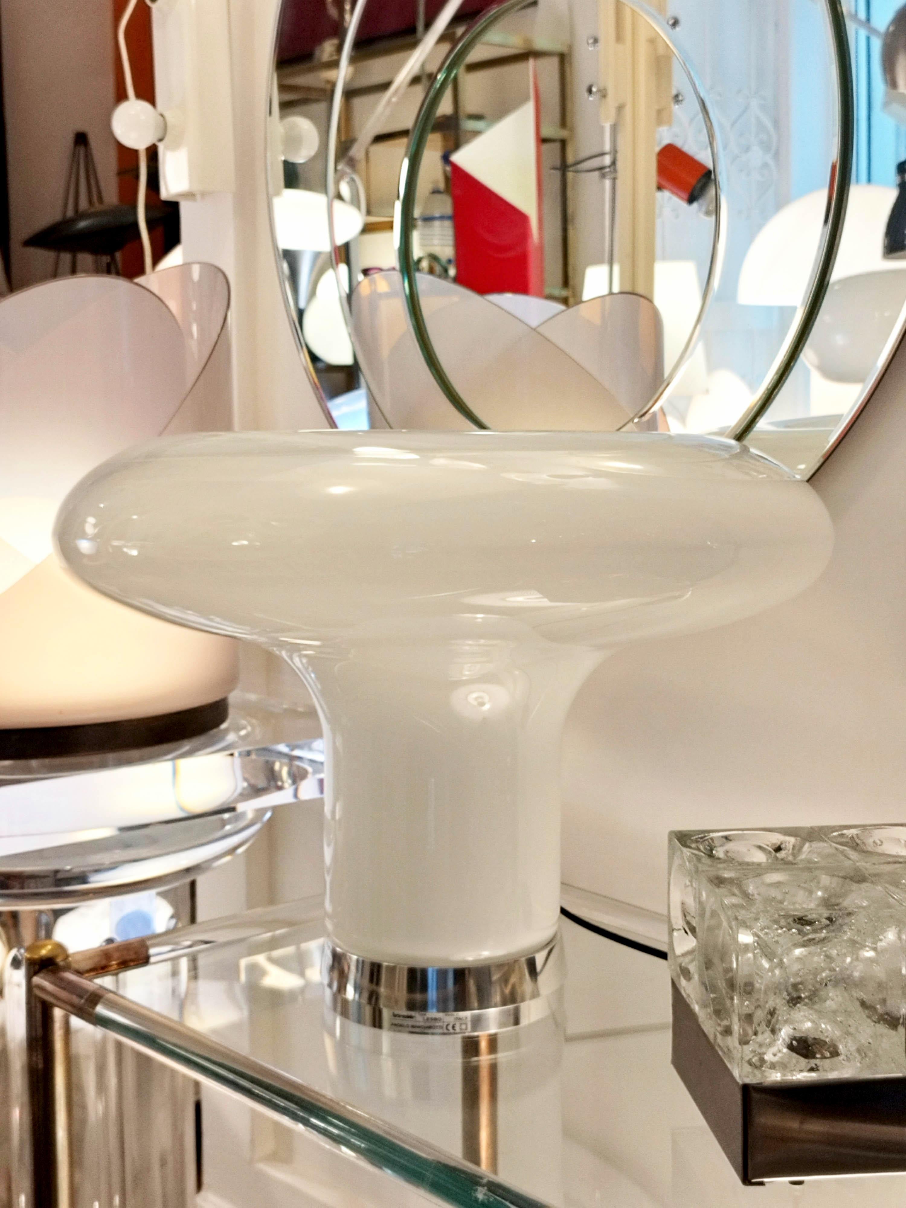 Lampe à poser Lesbo, l'une des lampes à poser les plus emblématiques. Conçu par Angelo Mangiarotti en 1967, il reste une icône de style et de raffinement, avec son corps et son diffuseur en verre soufflé-fumé de Murano et sa base en métal poli.