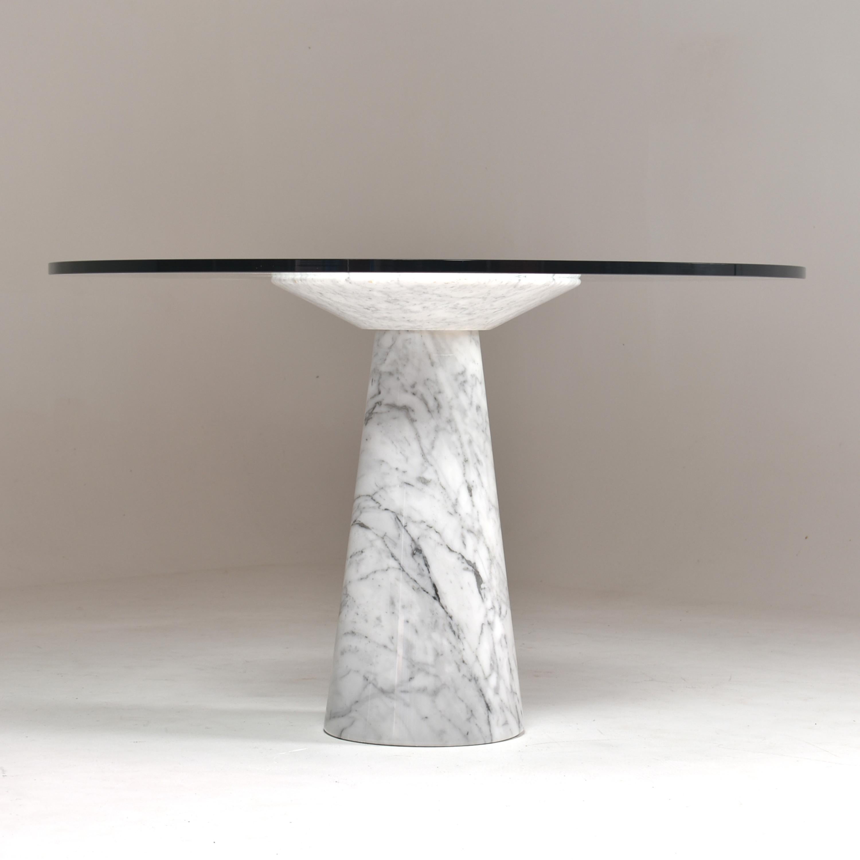 Round pedestal dining table, with a white Carrara marble leg, and round thick glass top.
In this work, the designer put the focus on the architecture of the leg, simple and classical play of volumes.
The glass top just sit on the polished marble,