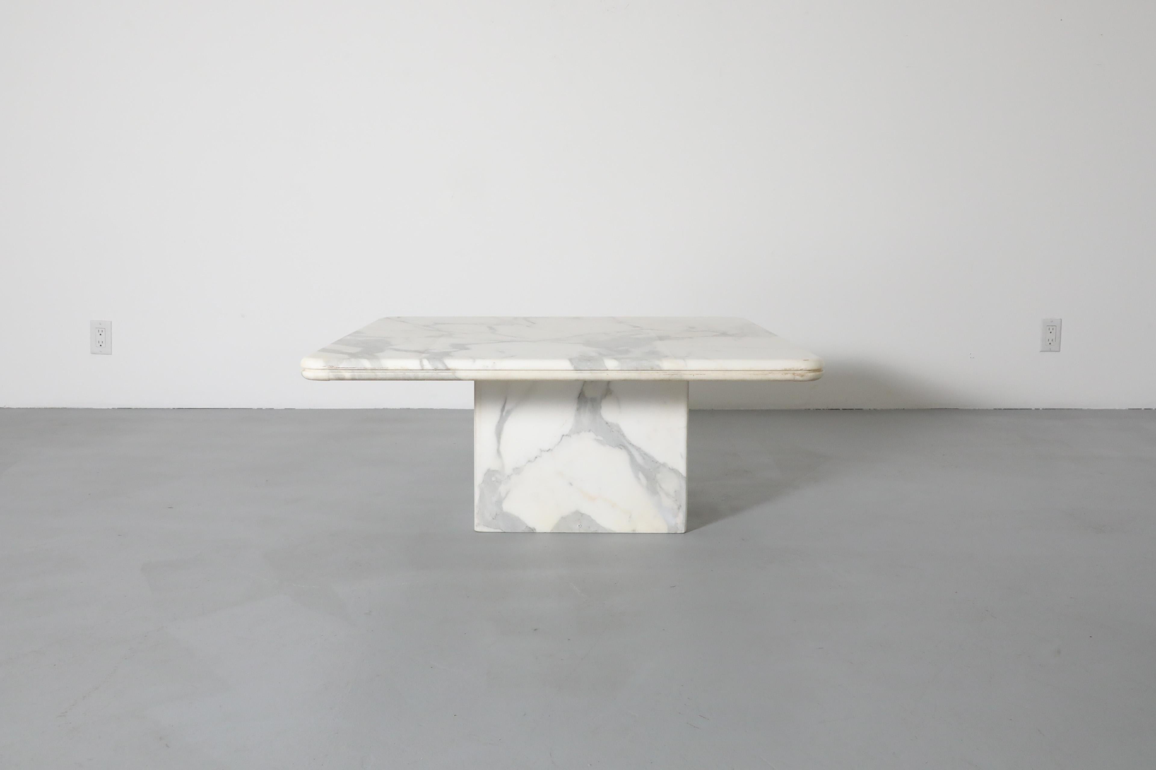 Elegant modernist marble coffee or side table. Heavy square marble top with curved corners and grooved edges resting unattached atop a cube marble base. In original condition with some noticeable irregularities including scratches, chips, signs of