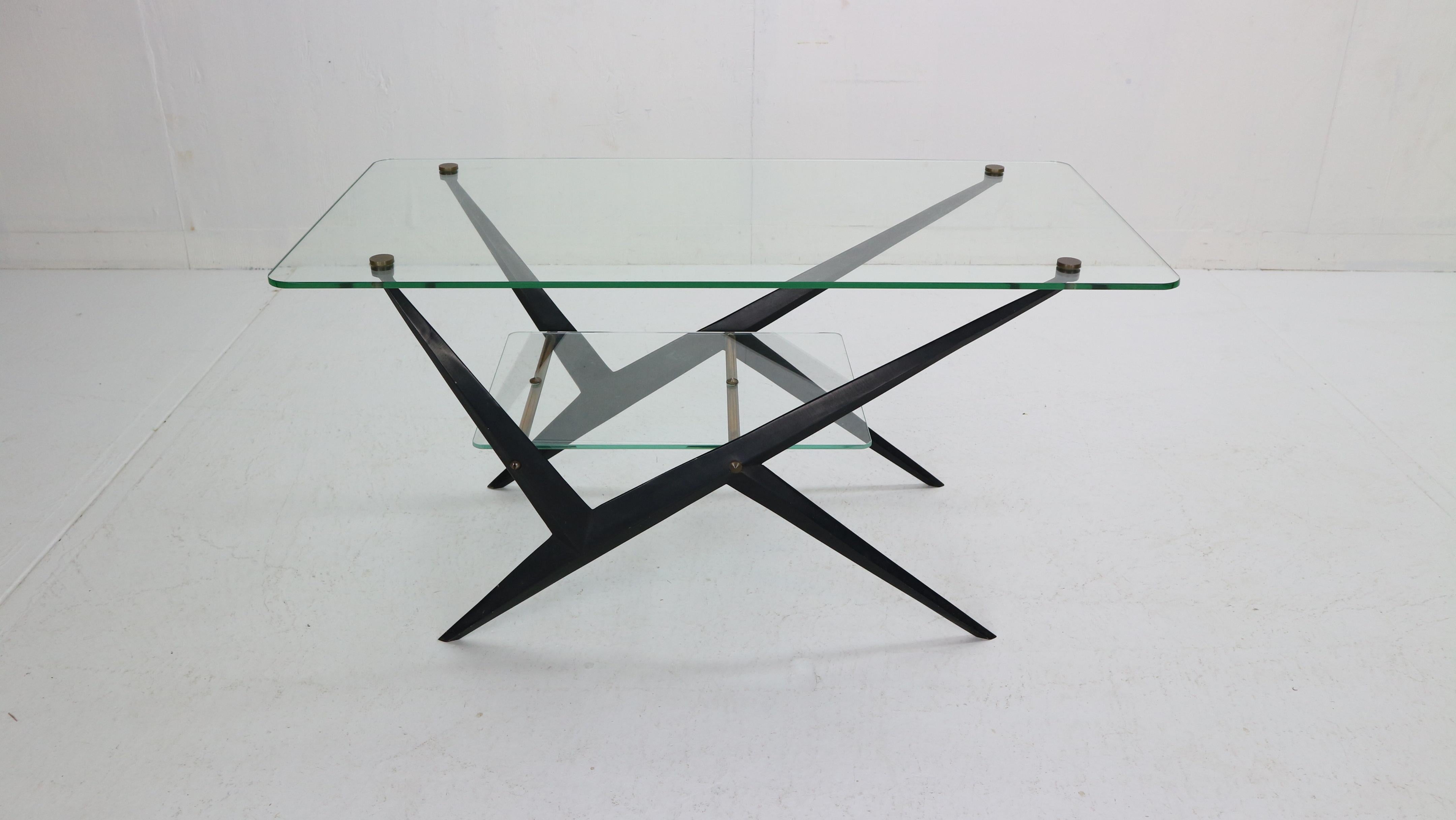 Mid-Century Modern dynamic coffee or cocktail designed and made by Angelo Ostuni, Italy, 1950s period. This table has a black lacquered metal frame and the brass details attach the glass tops between and on the base.

The top glass shelve has been
