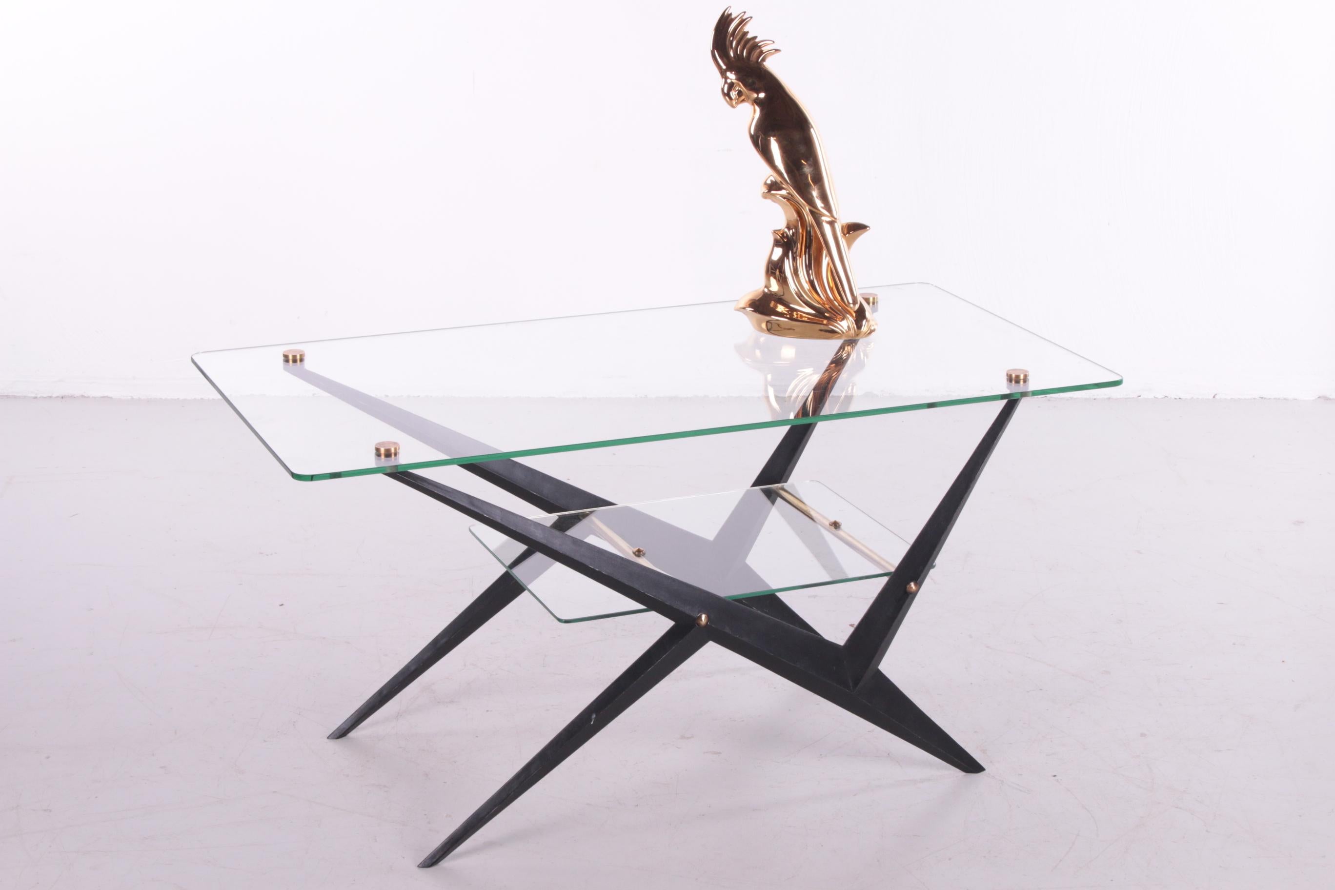 A beautiful and stylish cocktail/sofa table designed and made by Angelo Ostuni in Italy around the 1950s.

This table has a black lacquered metal frame and the glass tops between and on the base are attached with beautiful brass details.

The