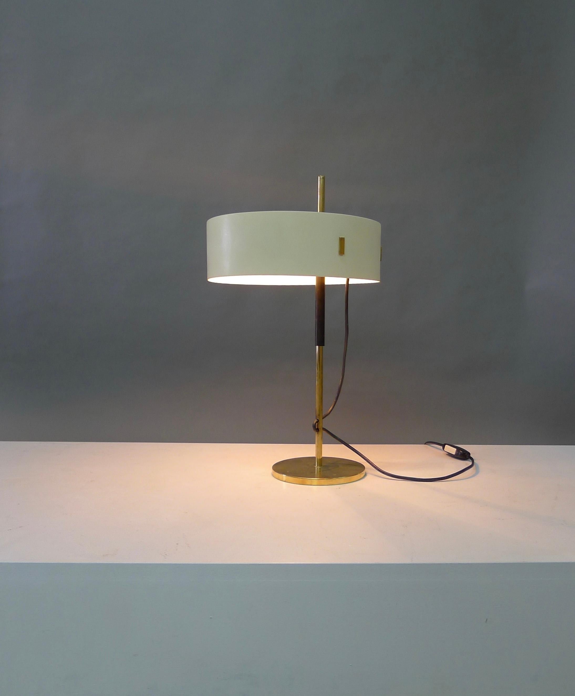 Angelo Ostuni and Roberto Forti for Oluce, Italy, Model 243 desk or table lamp with cream metal shade over brass supporting framework. 
The shade is height adjustable on the central pole.