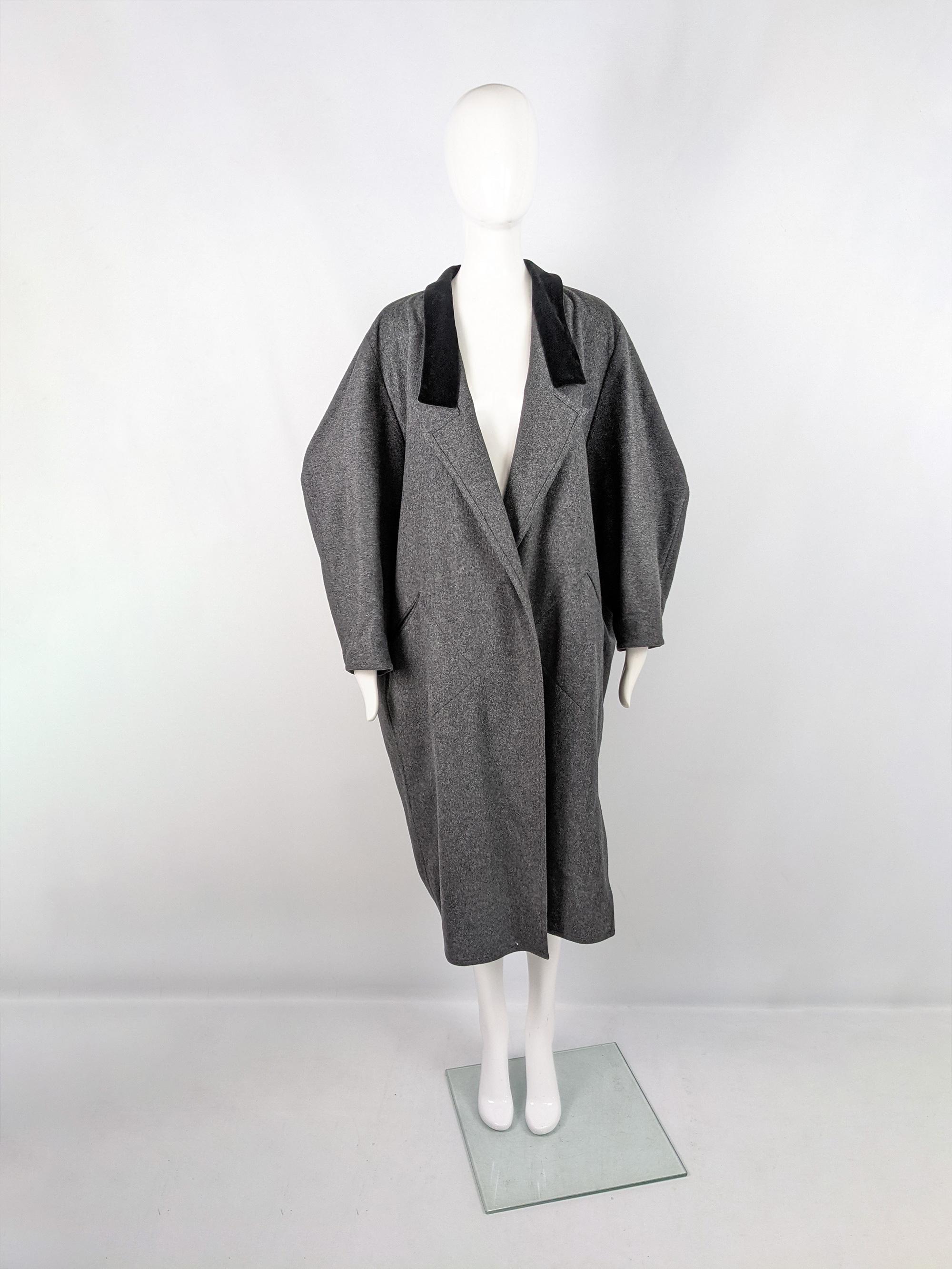 An incredible vintage coat from the 80s by iconic Italian born fashion designer, Angelo Tarlazzi. In a grey wool with a black velvet collar and a sculptural, architectural cocoon cut that is wider at the top and tapers in at the hem. The sleeves