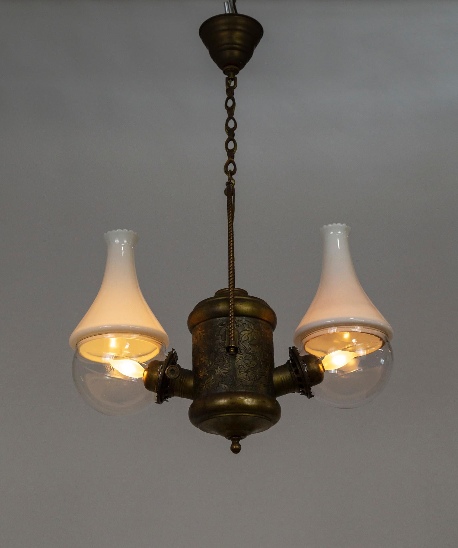 This is an 1890s double light, hanging fixture by The Angle Lamp Co. that was originally lit by kerosene, and is now electrified. Its oil lamps were unique, with the burner on the side at nearly a 90-degree angle to the body of the lamp. It has the