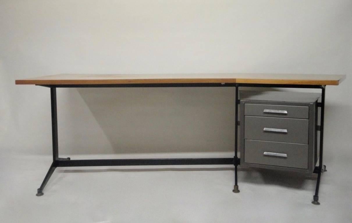 Executive desk manufactured by Tecno comprises a squared boomerang shaped wood top, a black enameled base with brass feet and three grey enameled metal pull-out drawers.