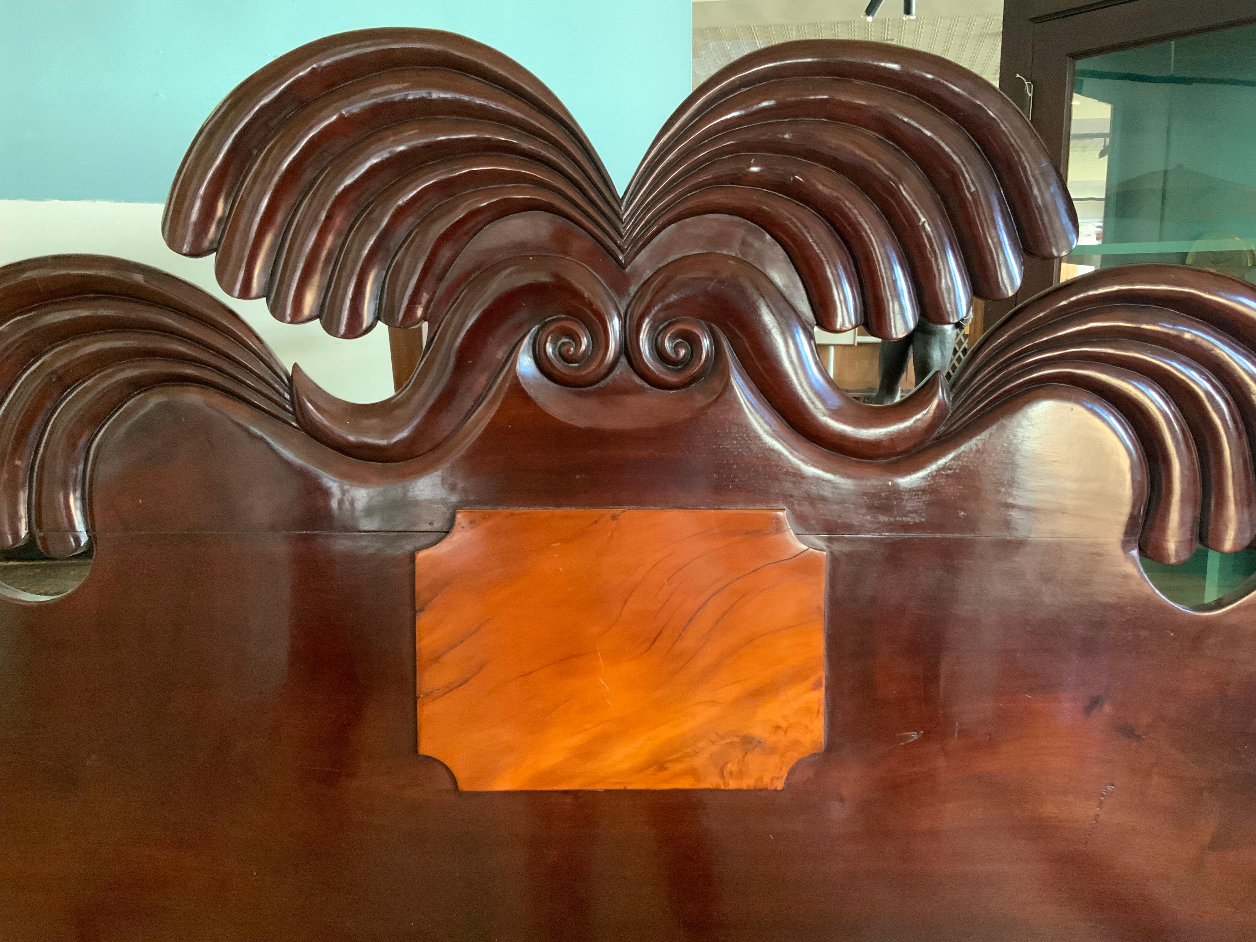 This elegant Caribbean mahogany bed was hand carved in the 19th century in Jamaica. This Rare West Indies Bedstead exhibits a scarce and desirable hand carved iconic Jamaican Double Waterfall headboard which resonates with the four solid mahogany