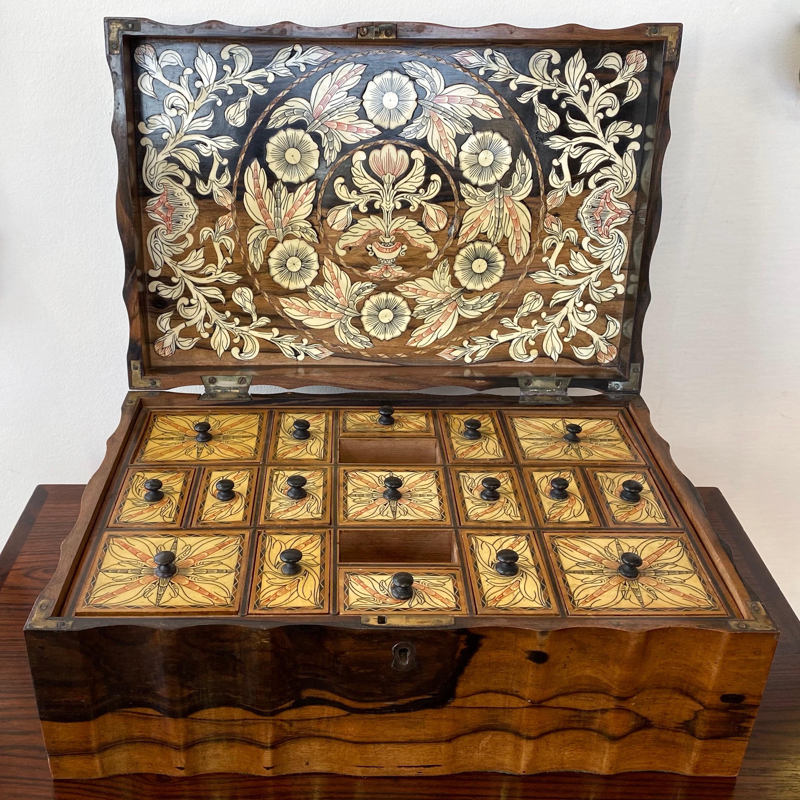 A very striking late 1800s Anglo-Ceylonese coromandel work, sewing, or companion box with exceptional bone, wood, and brass inlay and decoration.

Case of handsomely figured and variegated coromandel (calamander) veneer with serpentine sides. Hinged