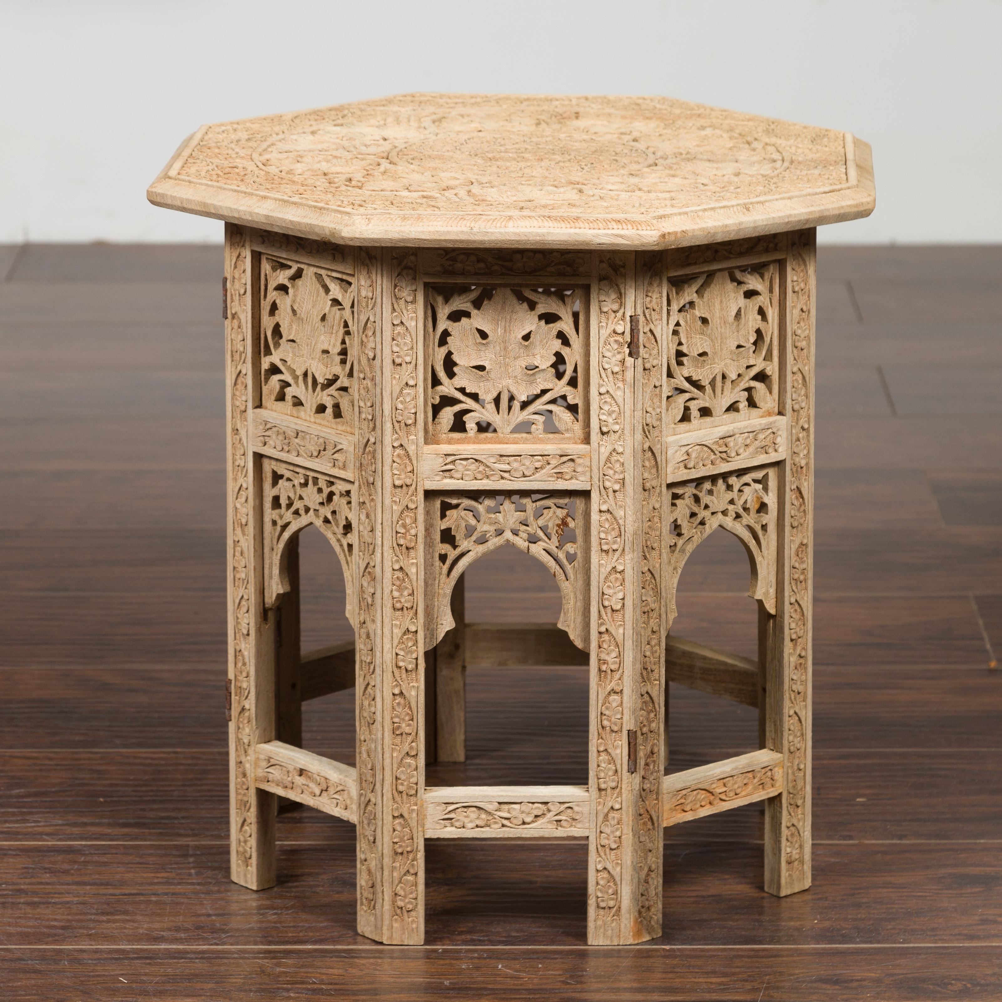 An Anglo-Indian period bleached side table from the mid-20th century, with richly carved foliage motifs. Created during the second quarter of the 20th century, this Anglo-Indian low side table features an octagonal top adorned with low-relief
