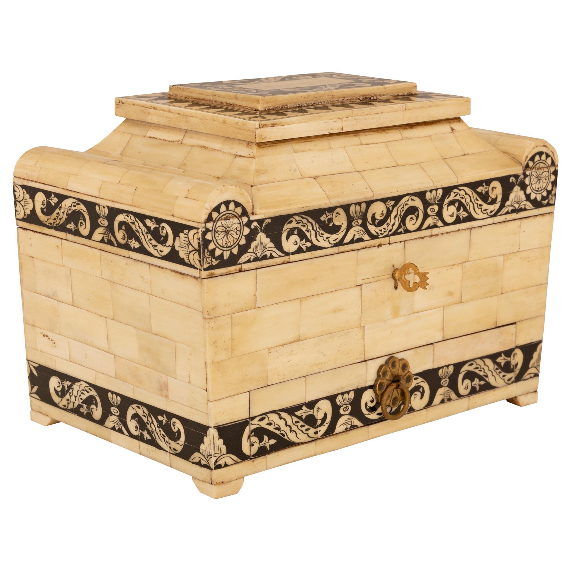 Una splendida e attraente scatola anglo-indiana del XIX secolo, patinata nera, in osso e Oak. Questa scatola rettangolare unica nel suo genere, realizzata con blocchi di osso impiallacciato, è sostenuta da quattro piedi quadrati. Lungo la base del