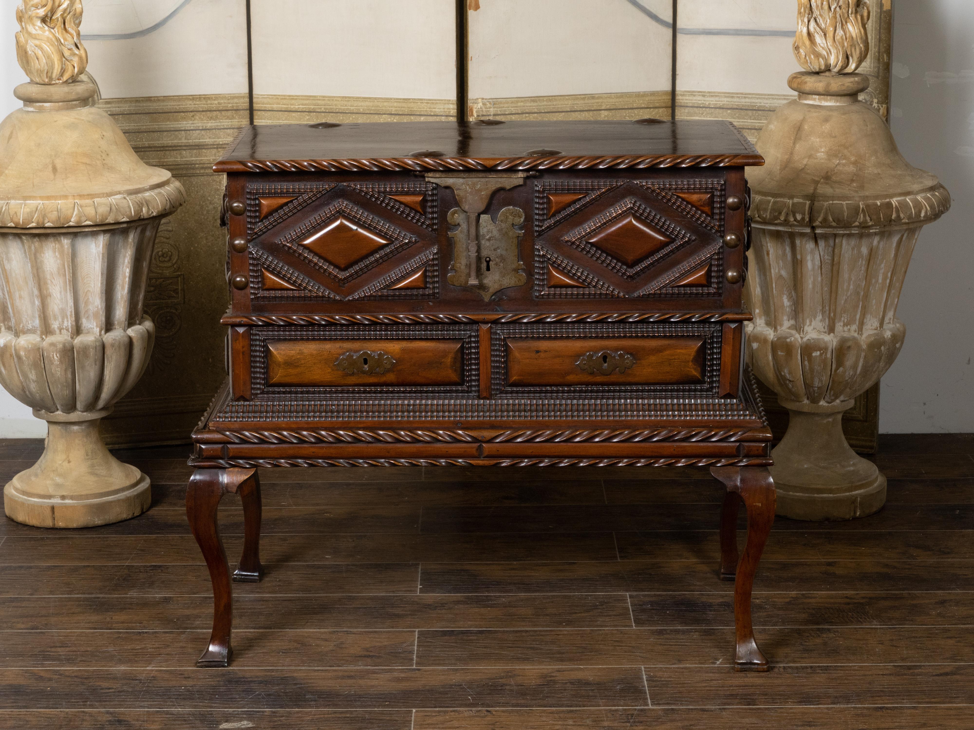 An Anglo-Indian geometric front mahogany coffer on base from the 19th century, with lift top, carved panels, two drawers, cabriole legs and lateral handles. Hand-crafted during the 19th century, this Anglo-Indian mahogany coffer features a