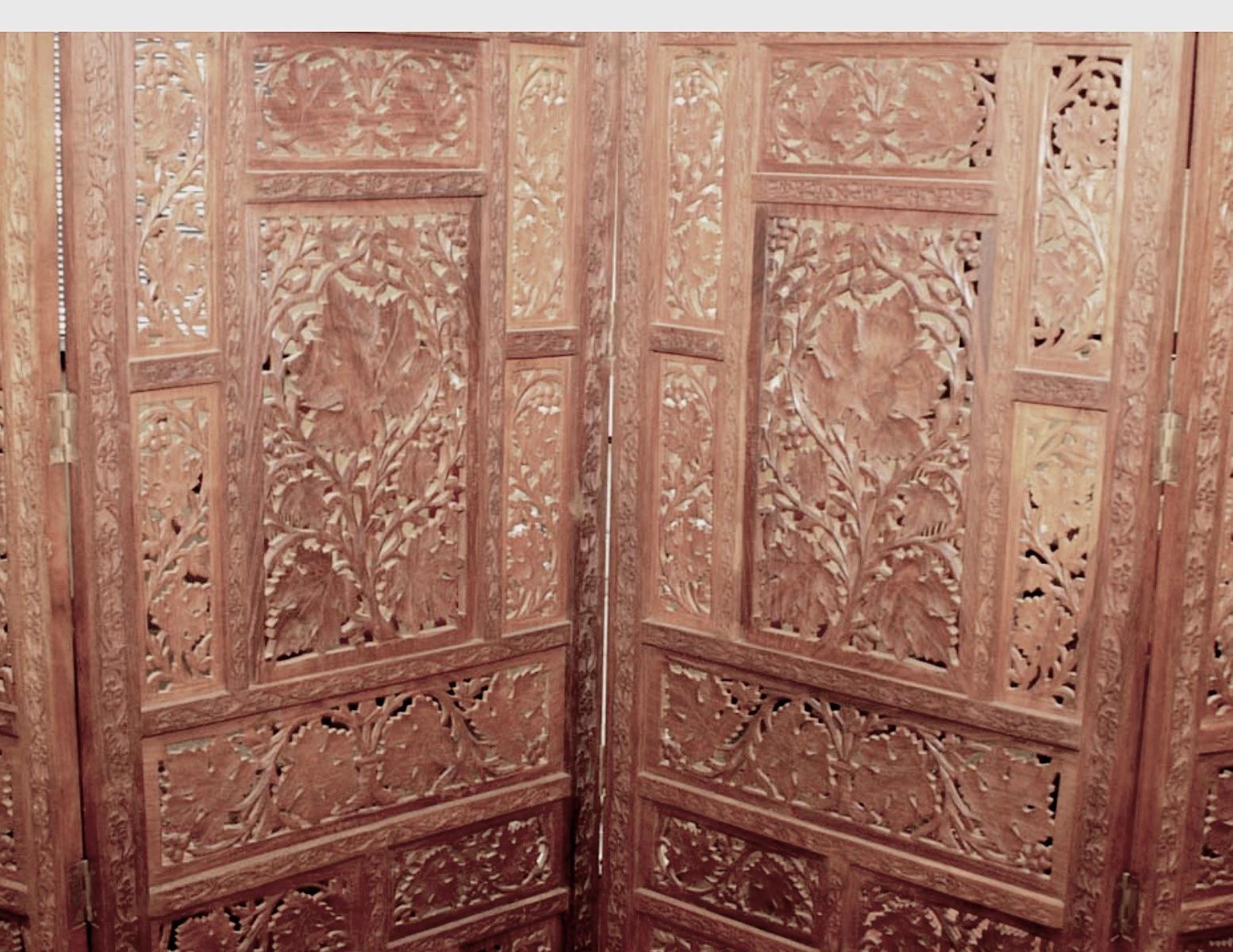 A lovely Anglo Indian elaborately hand carved teak wood 4 panel screen, circa 1900s.
A heavy substantial folding screen features intricate open work carved panels with an organic leaf motif. 
Fully Carved side moldings with finial style tops.
Top