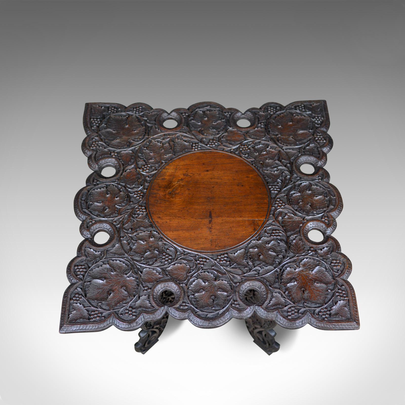 This is an Anglo-Indian, antique Campaign table. A vigorously carved teak side table dating to the turn of the 20th century, circa 1900.

Profusely carved in deep relief
Grape vine foliate detail
Pierced detailing to shaped edges and legs
Plain