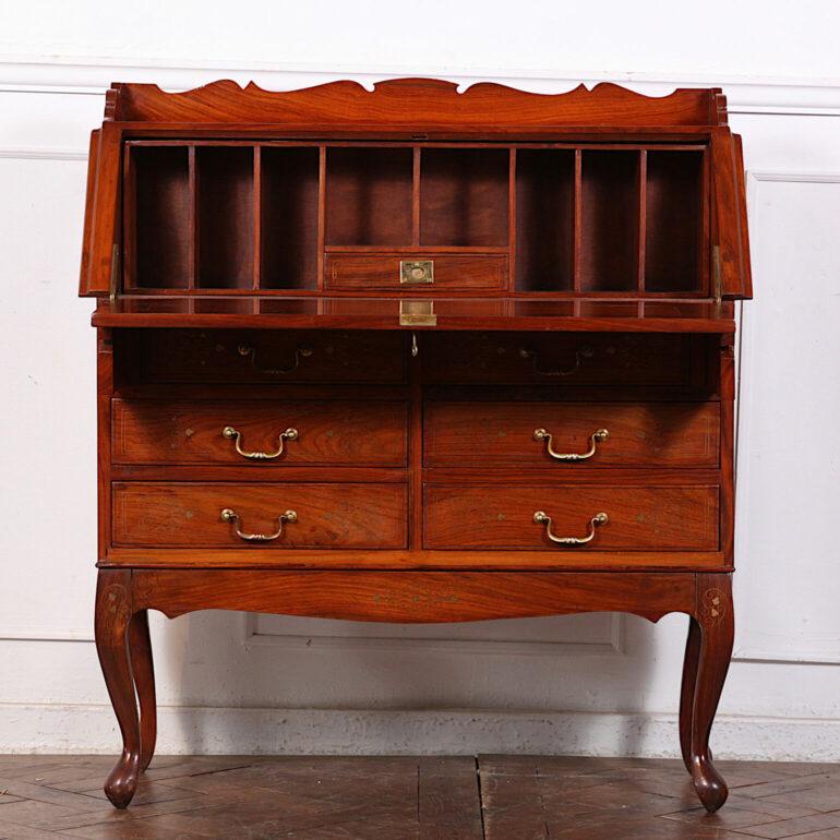 A solid teak and brass-inlaid Anglo-Indian drop-front bureau or desk, the case fitted with three drawers below a slant front which opens to provide a writing surface and access to the fitted interior. Raise of carved cabriole legs.