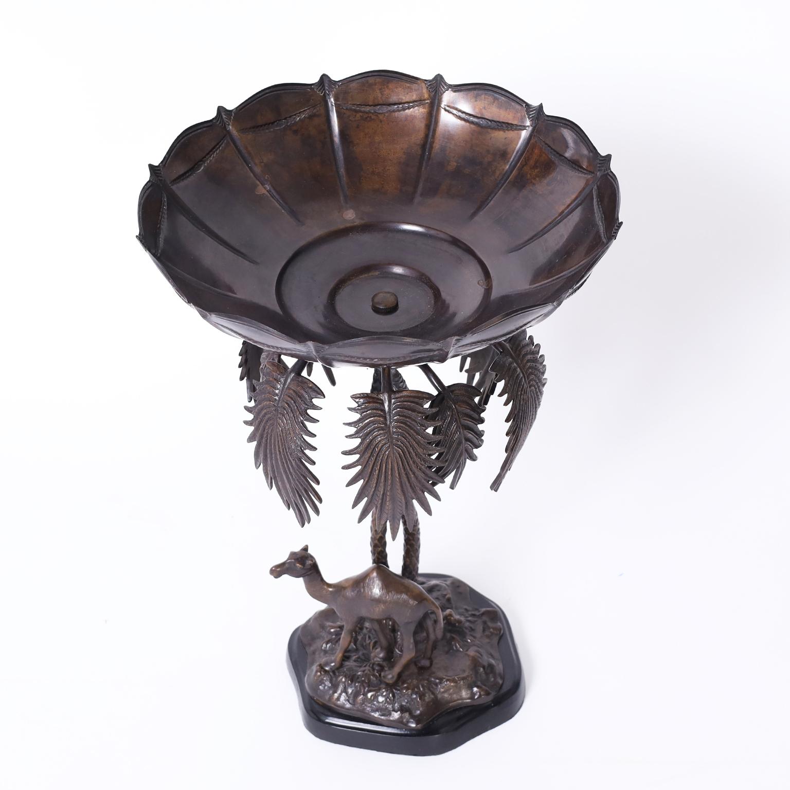 British colonial style cast bronze fruit or serving bowl on a palm tree stand over a camel on a faux terra firma base.
