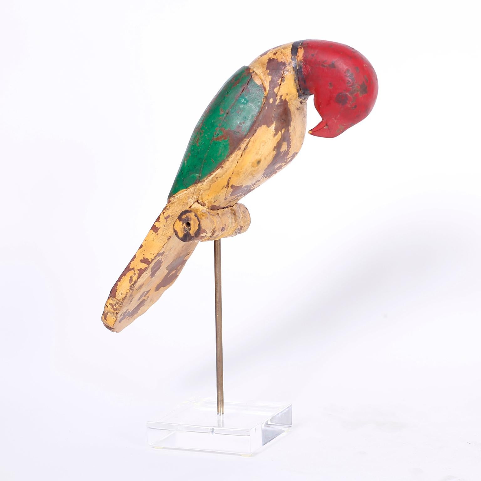 19th century Anglo Indian bird or parrot carved from indigenous hardwood in a naive style, retaining its original paint now worn to perfection and presented on a brass and lucite stand.
