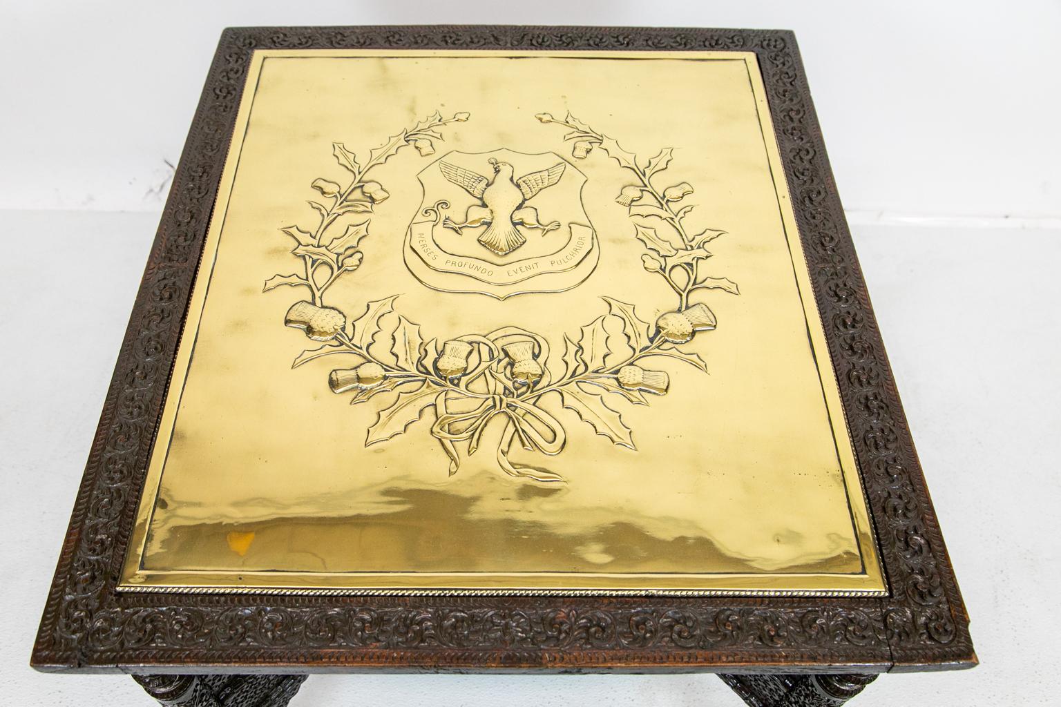 Anglo Indian carved brass top table, the base intricately carved with double cross stretchers. The top is raised with a heraldic eagle crest surrounded by a holly and thistle wreath. The brass inset is polished and lacquered for easy maintenance.