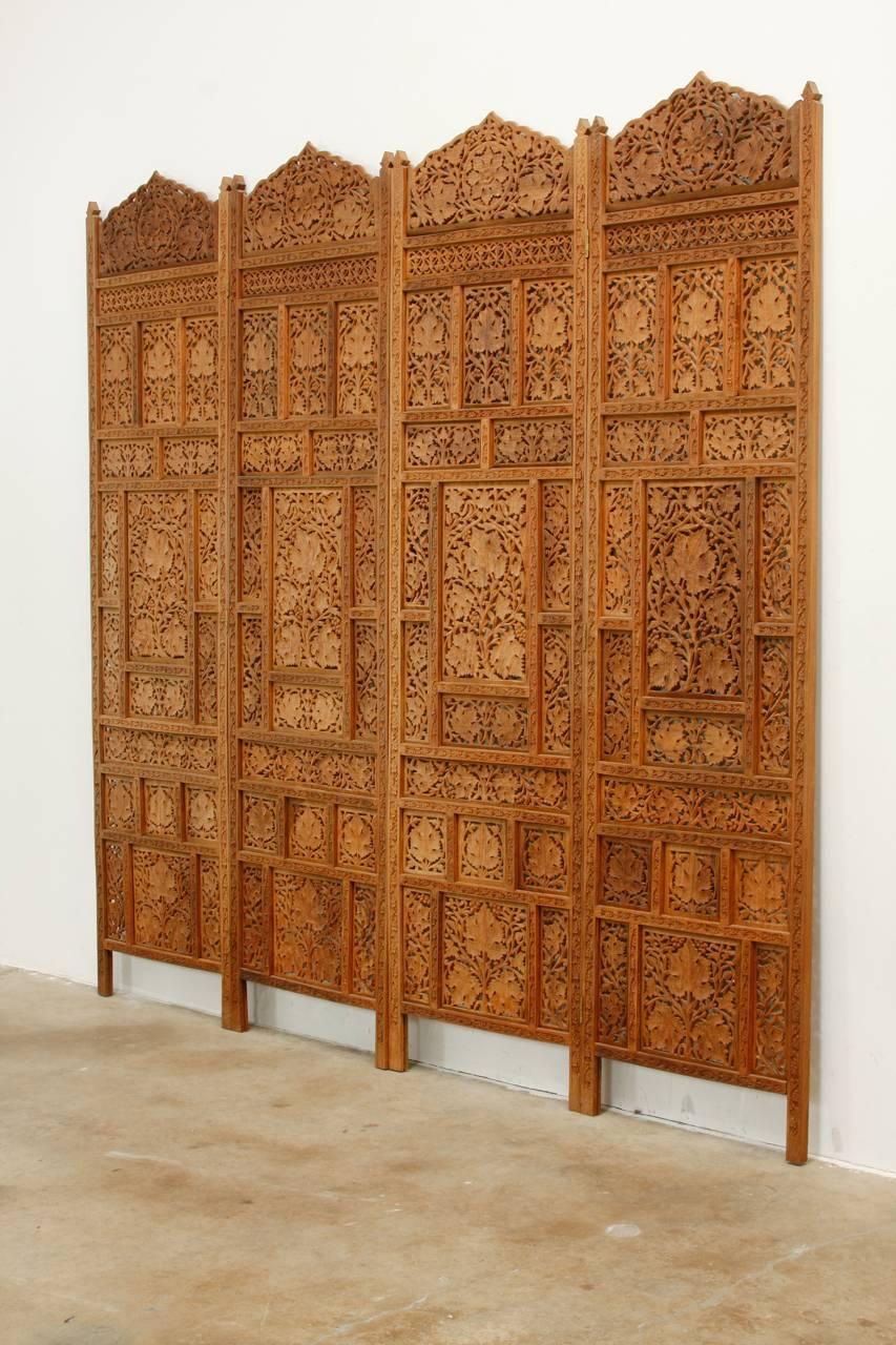 Large Anglo-Indian hand-carved teak four panel foliate screen. Features pierced windows with a foliate motif. Heavy and solid in excellent condition. Can be displayed flat or folded with hanging hardware on the back side.