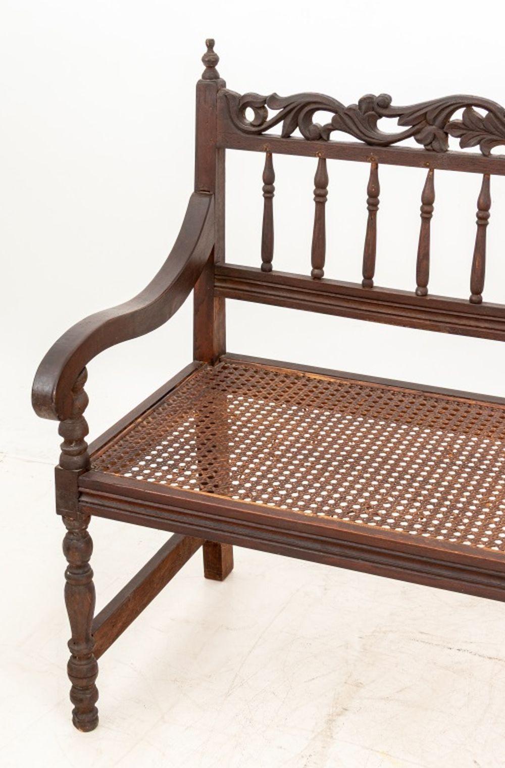Anglo-Indian Carved Hardwood Hall Bench, with carved and spindle back and cane paneled seat. 39.5