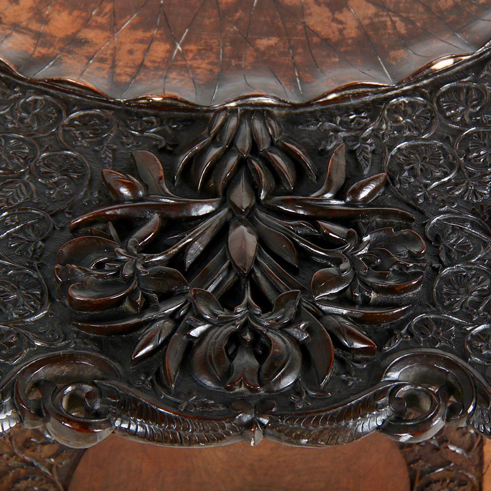 A highly-carved octagonal side table, likely South-Asian, with a folding base and removable top.
Each of the eight base panels is pierce-carved with foliage and leaves, and supports a top with central lotus blossom surrounded by minutely carved