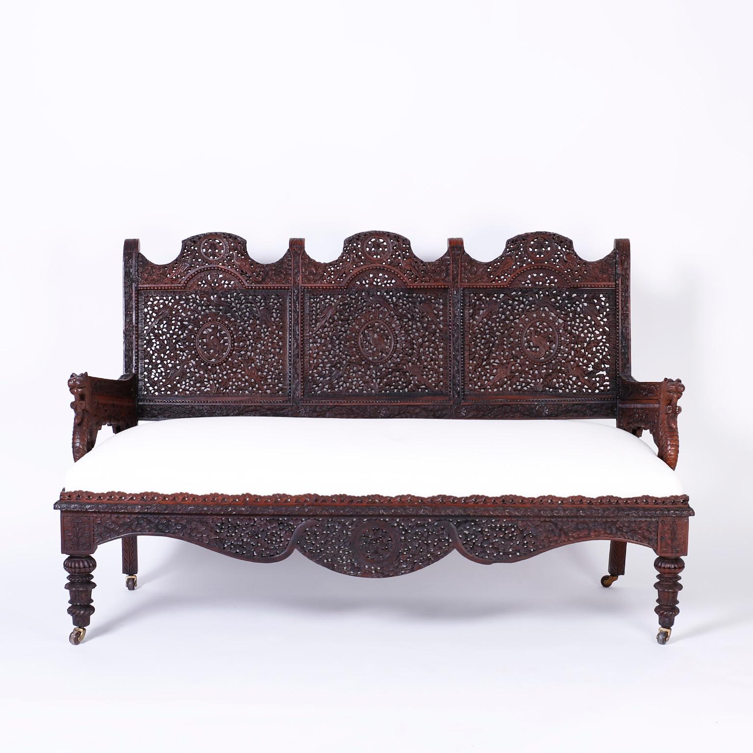 Antique Anglo-Indian hand carved mahogany sofa or settee with elaborate carvings throughout, featuring three back panels with bird medallions in a floral field, serpent arms, floral carved skirt and turned and carved front legs. Best of the Genre.