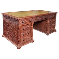 Scrivania anglo-indiana intagliata in teak a ginocchio