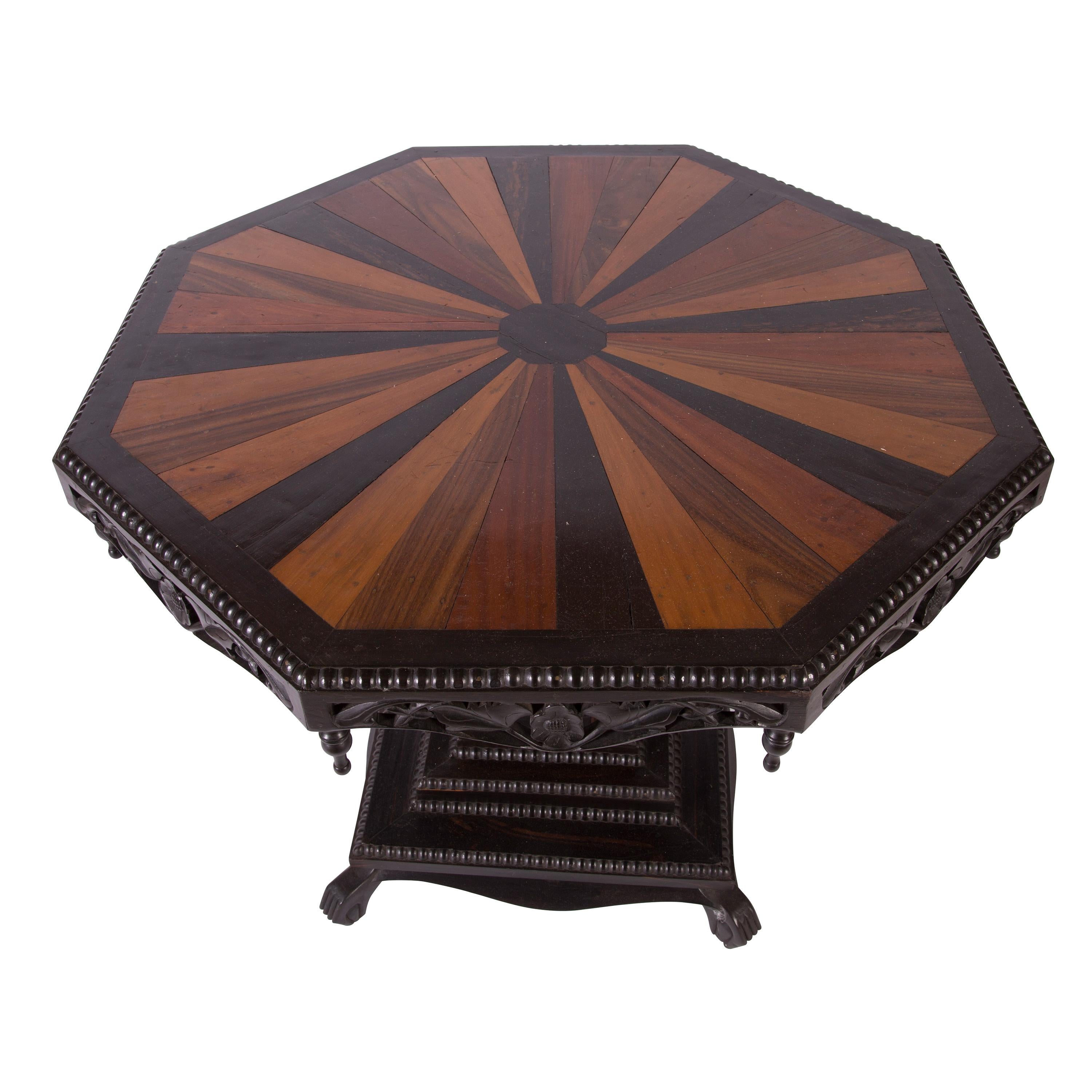 An Anglo-Indian carved ebony octagonal centre table with specimen wood segmented top, circa 1900.
